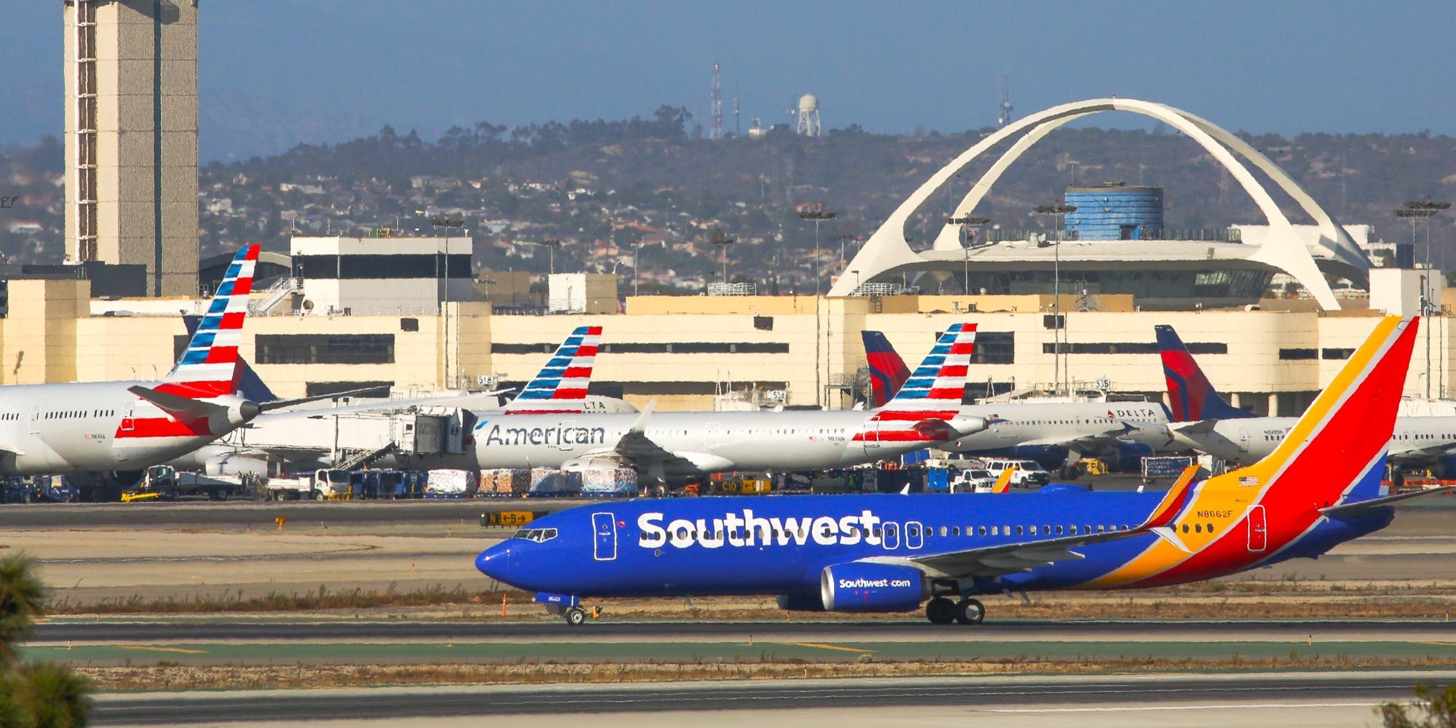 A Southwest Airlines plane lands at Los Angeles International Airport next to American Airlines planes.