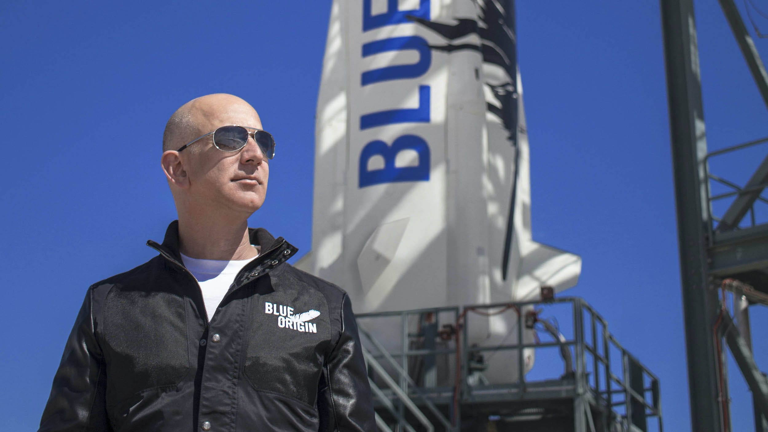 Jeff Bezos looks into distance in front of Blue Origin rocket