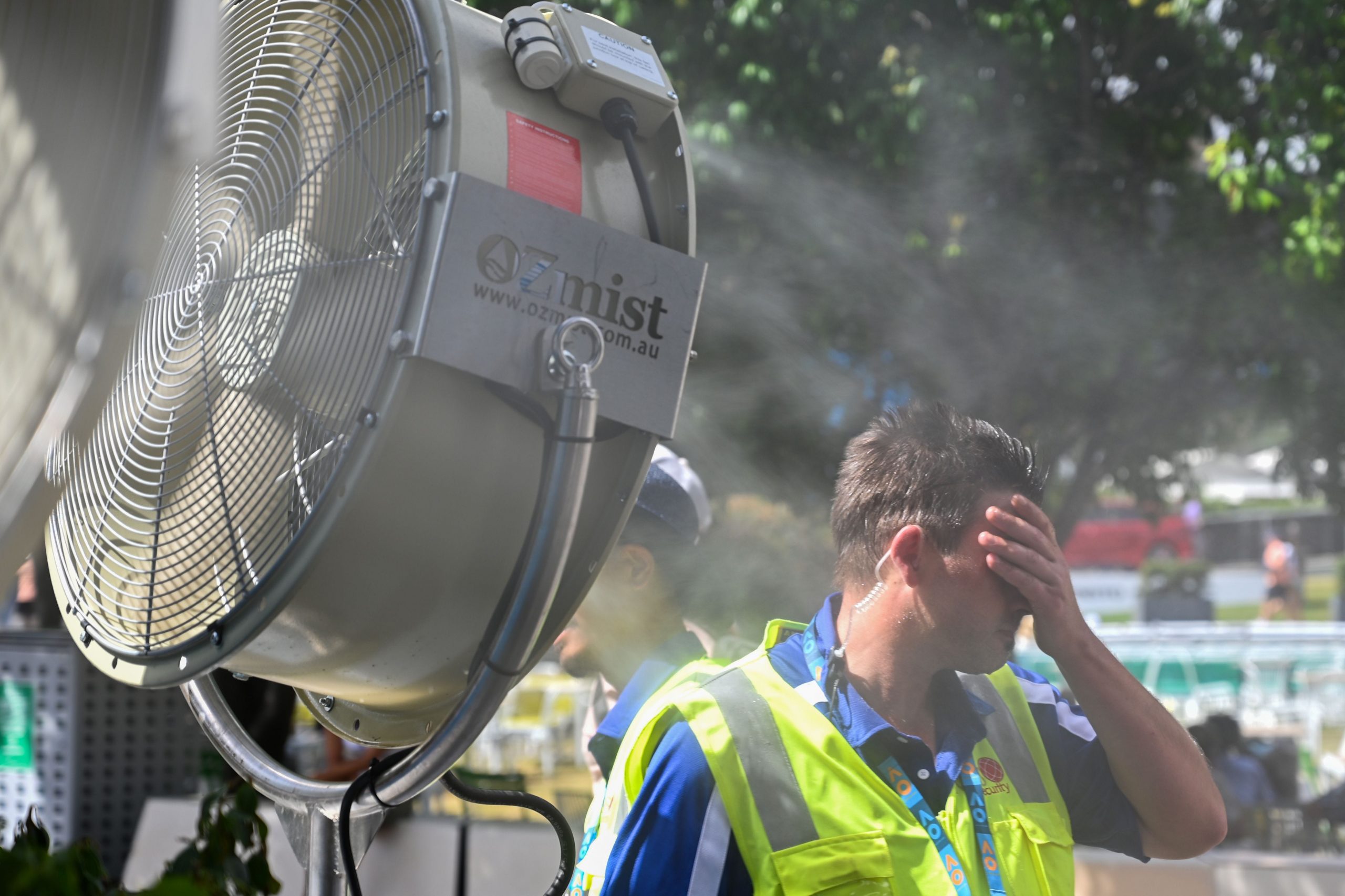 A man wipes sweat from his face in sweltering heat.