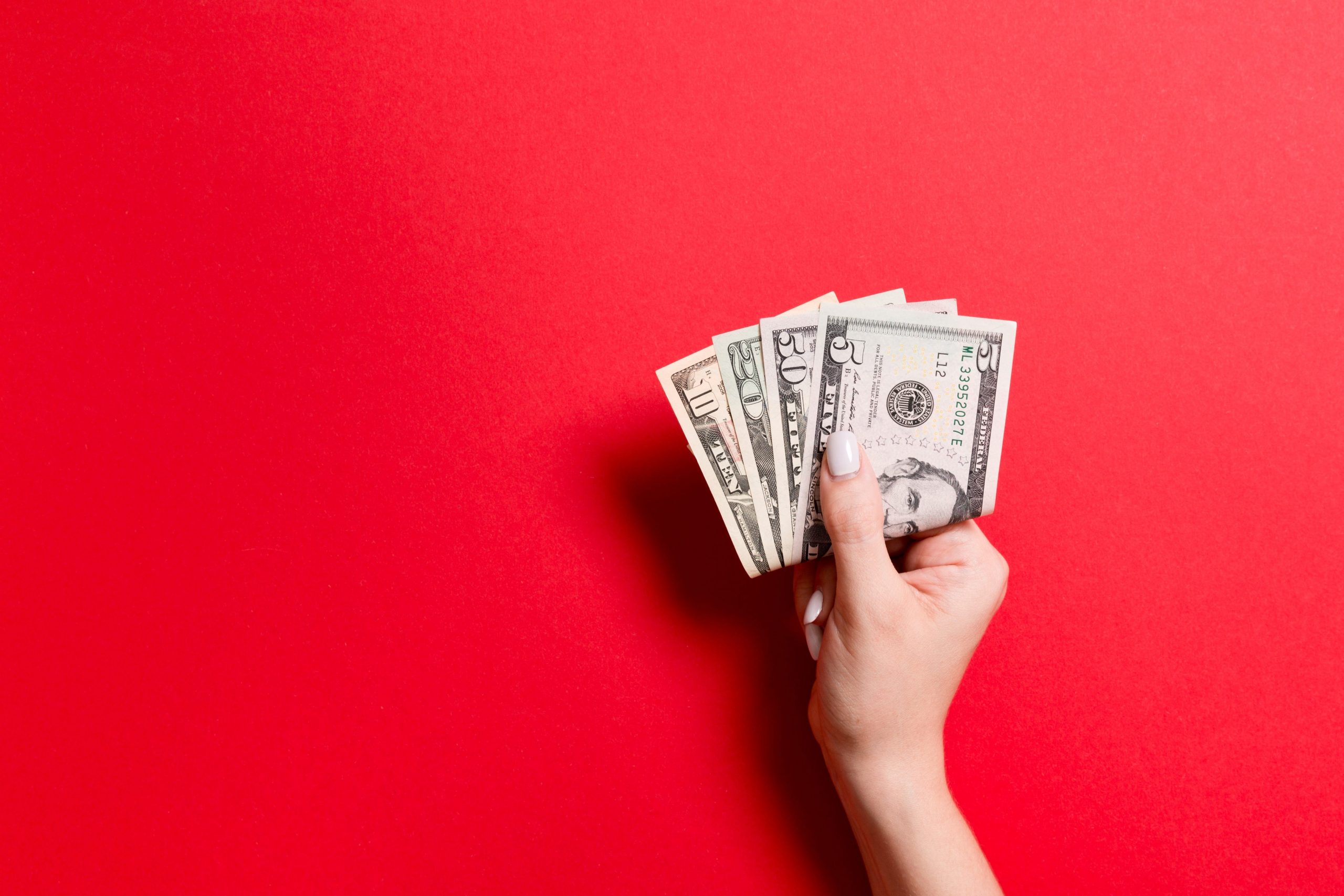 A photo of woman's hand holding $20 bills.