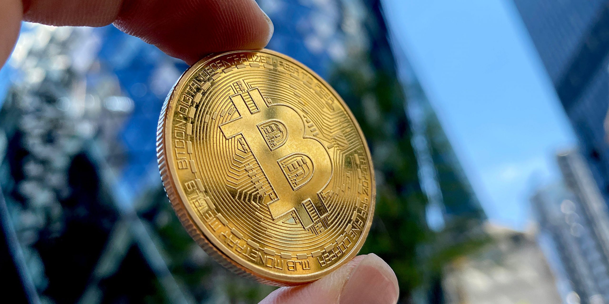 A hand holds a bitcoin toward the sky in this photo representation of the cryptocurrency.