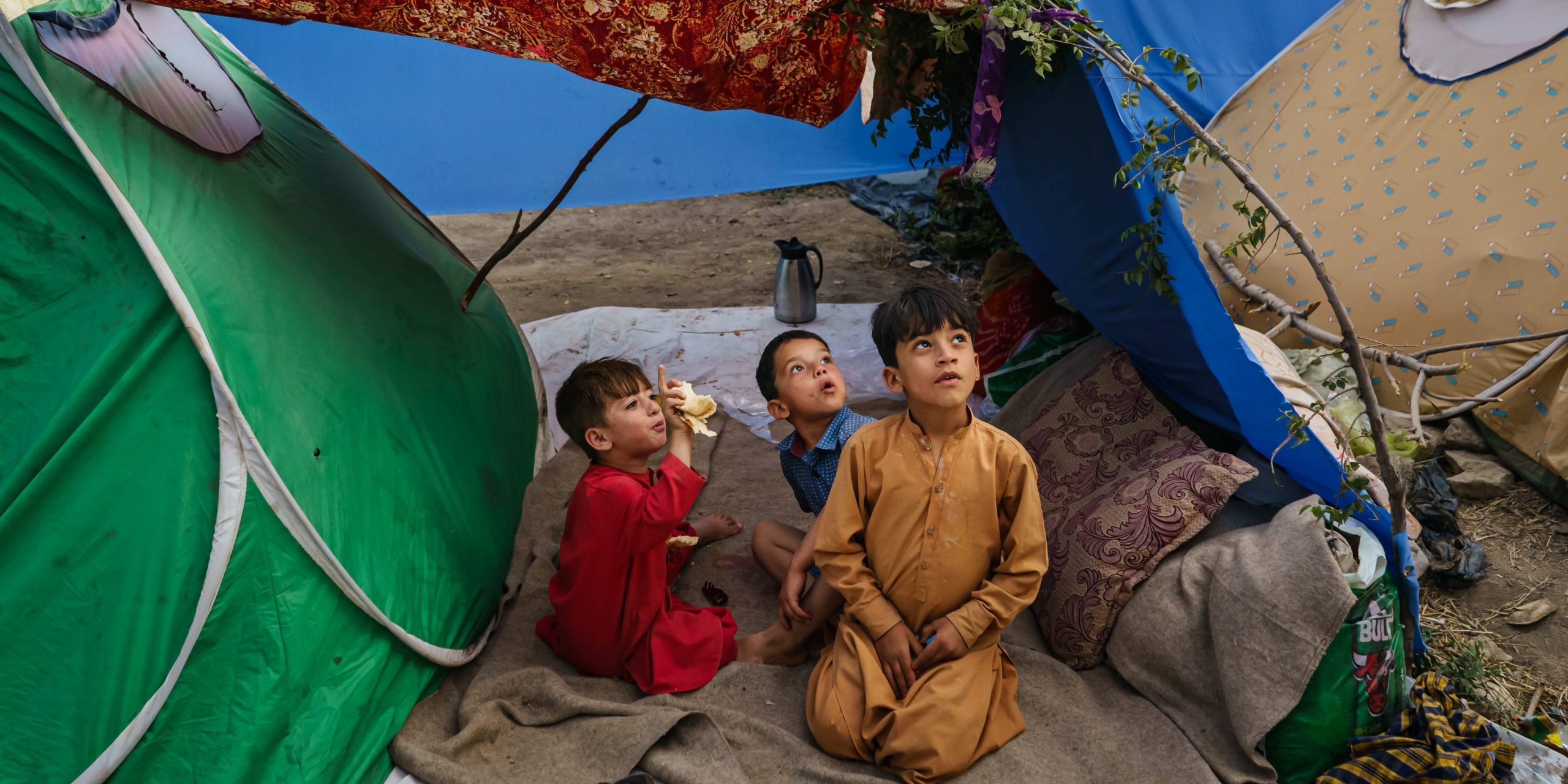 Afghan children look at a passing aircraft a makeshift camp for displaced Afghans fleeing the fighting between the Taliban and the Afghan Security Forces at Hasa-e-Awal Park, in Kabul, Afghanistan, Saturday, Aug. 14, 2021.