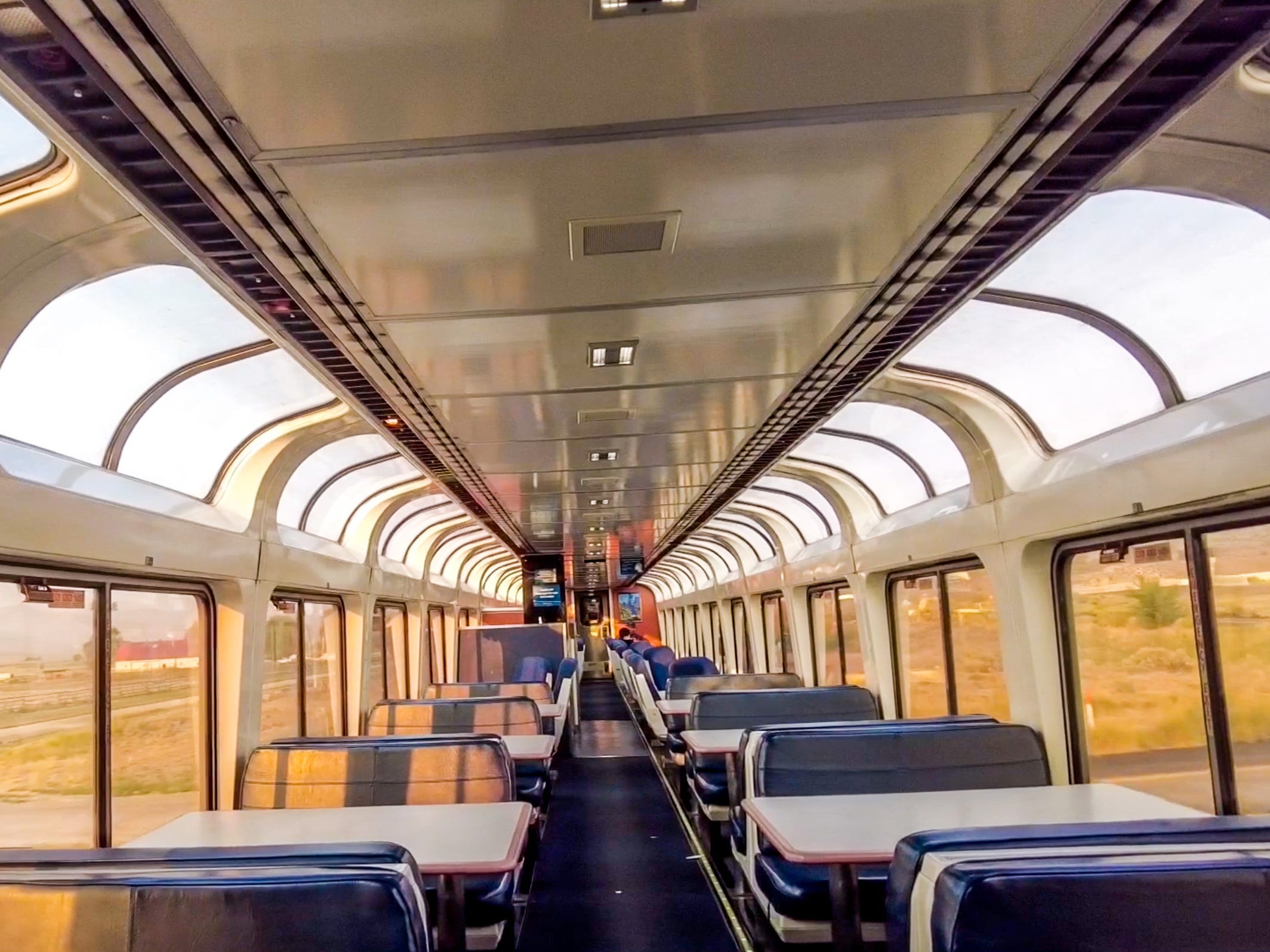 A view of the Amtrak observation car, which is full of windows and blue seats