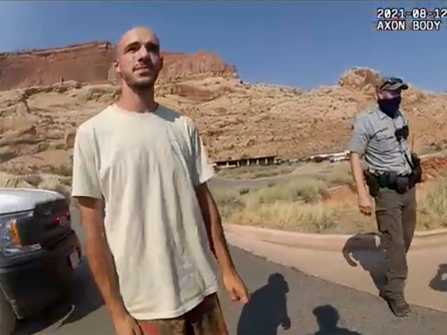 Brian Laundrie in the desert with a cop behind him