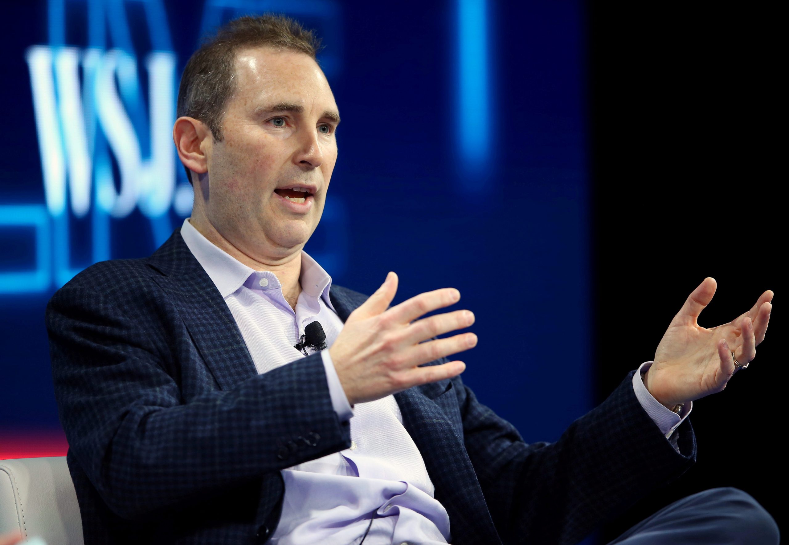 Amazon CEO Andy Jassy motions with his hands on stage at a conference.