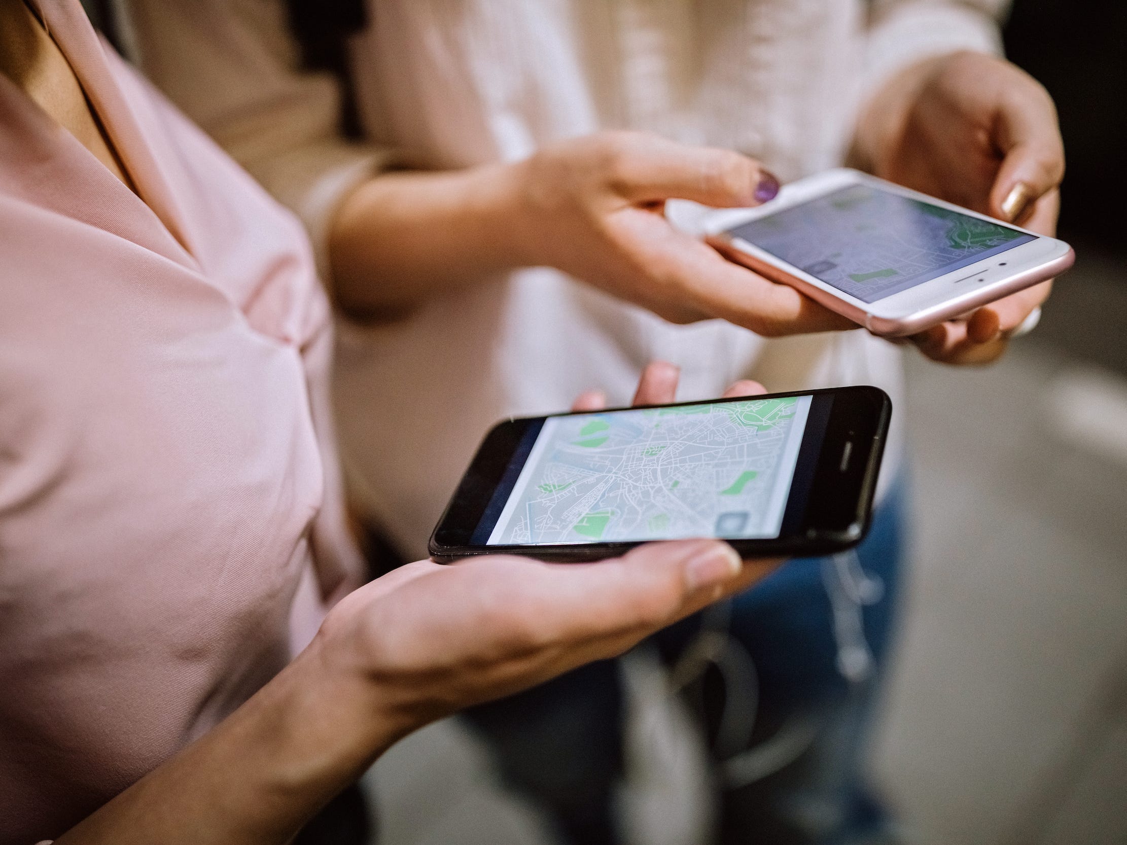 hands holding phones looking at maps on phone