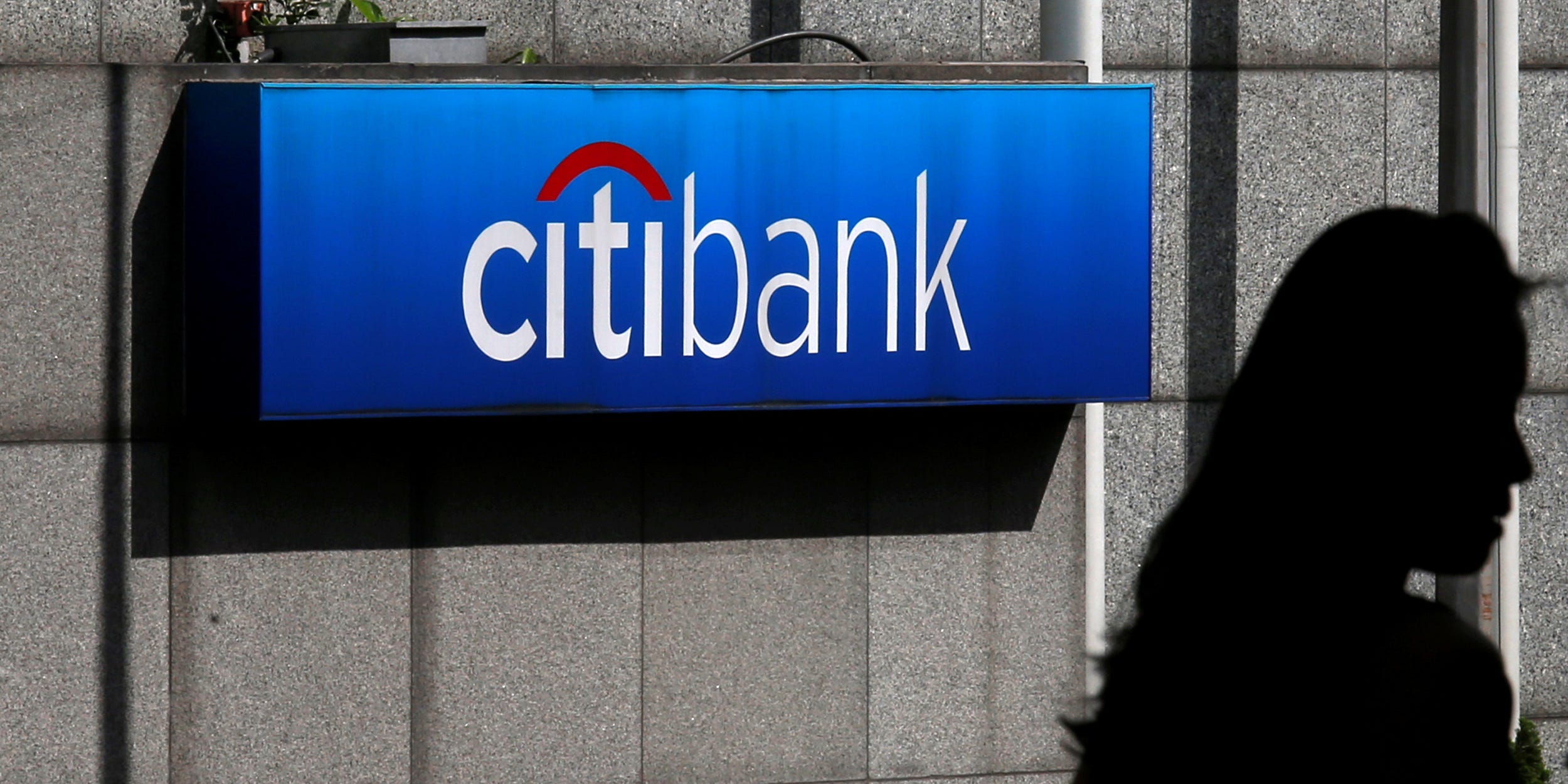 FILE PHOTO: A woman walks past a Citibank logo displayed outside the Citibank Plaza in Hong Kong July 28, 2014. Picture taken July 28, 2014.  REUTERS/Bobby Yip