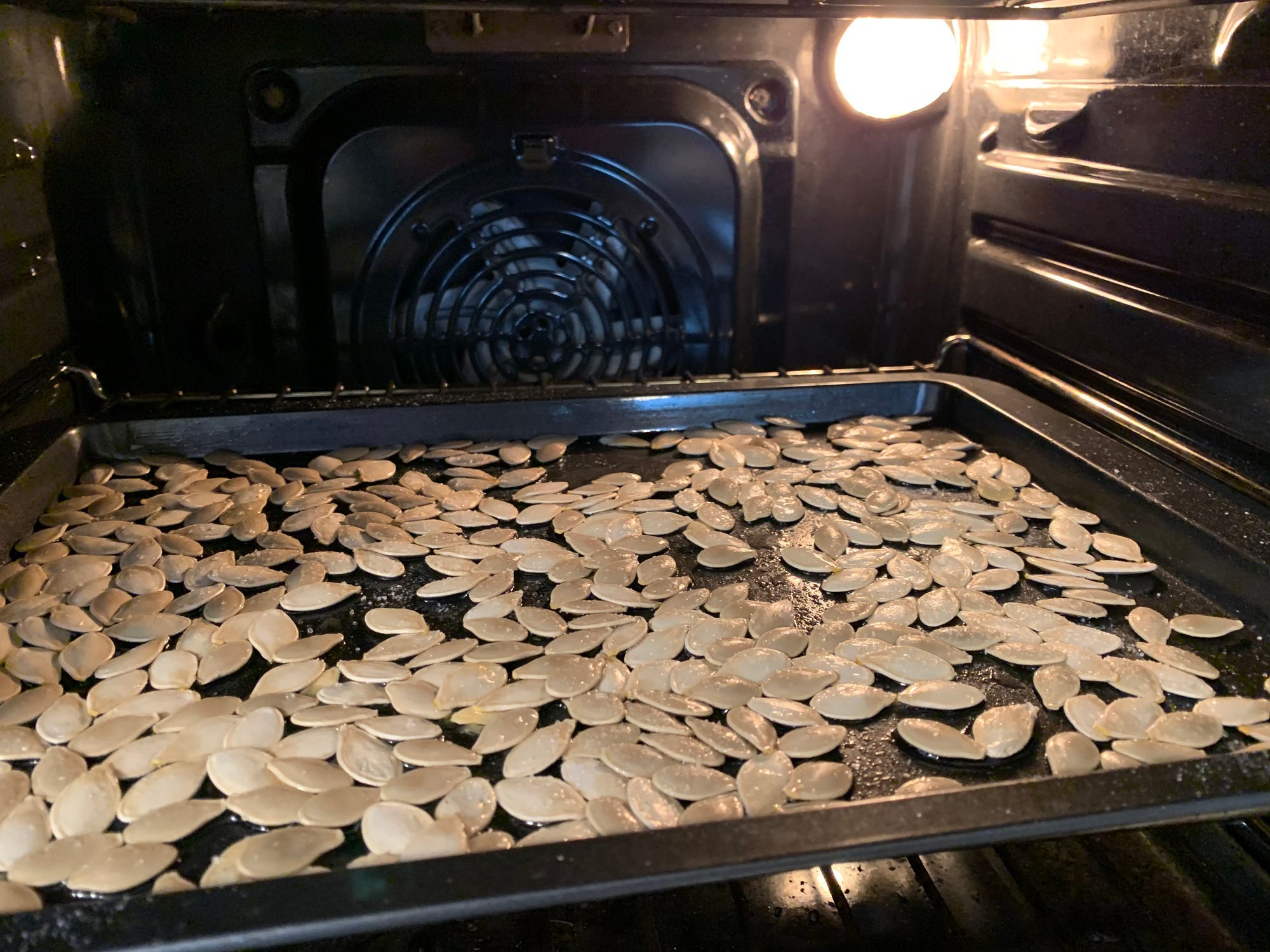 A tray of pumpkin seeds in the oven.