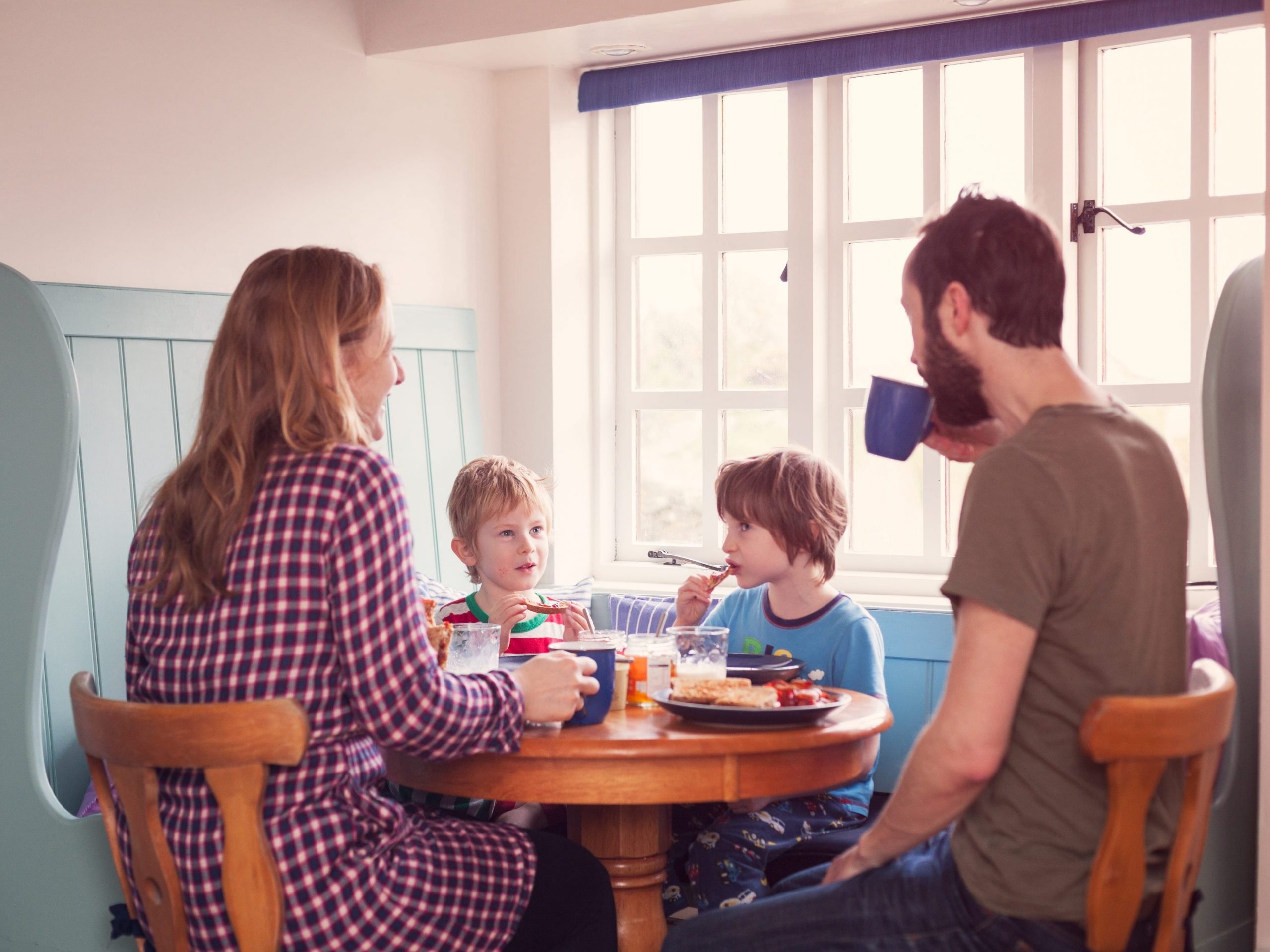 A young family having breakfast together in a cottage by the sea.