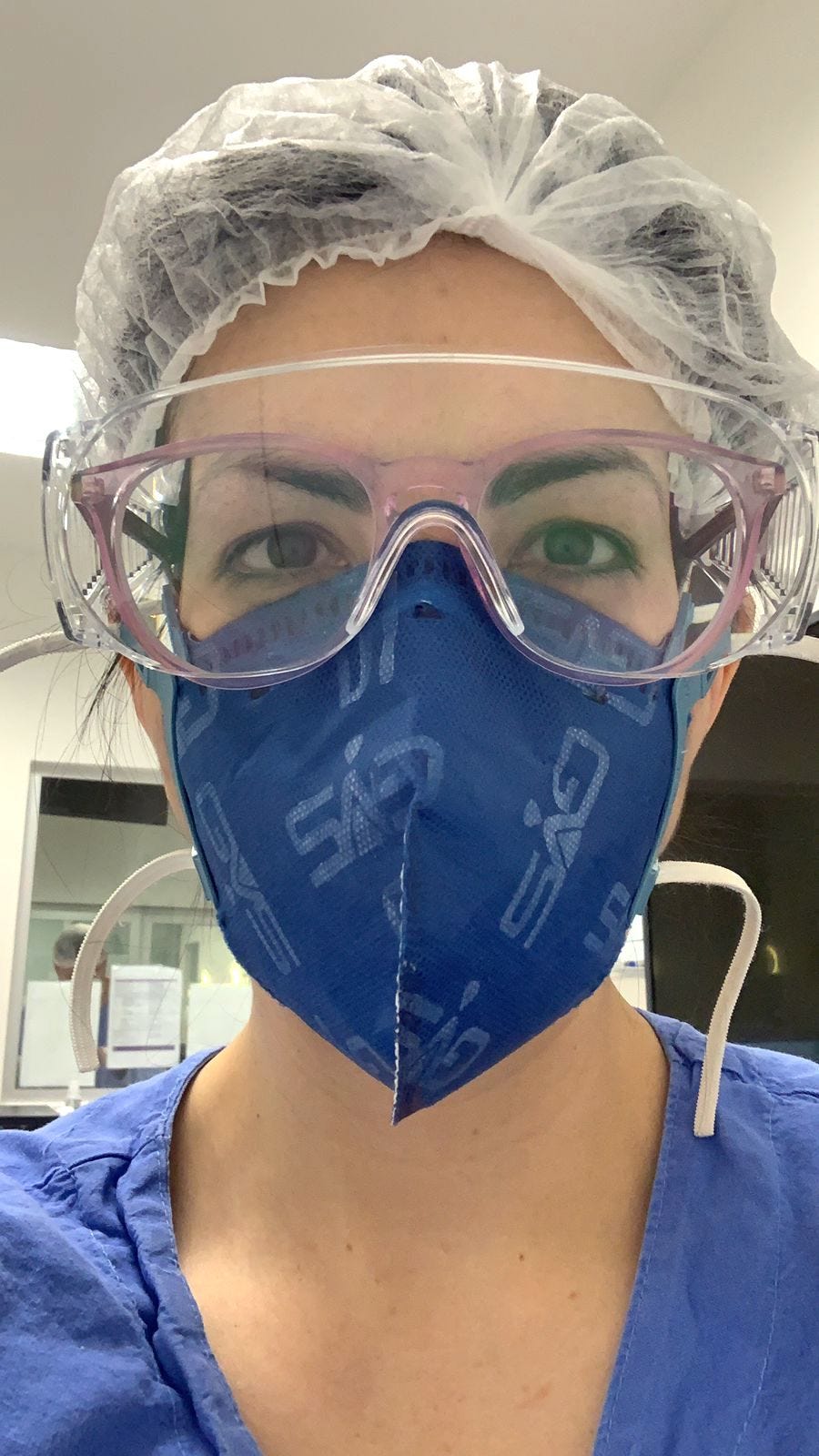 close up of ICU doctor in scrubs, mask, goggles, and hair net