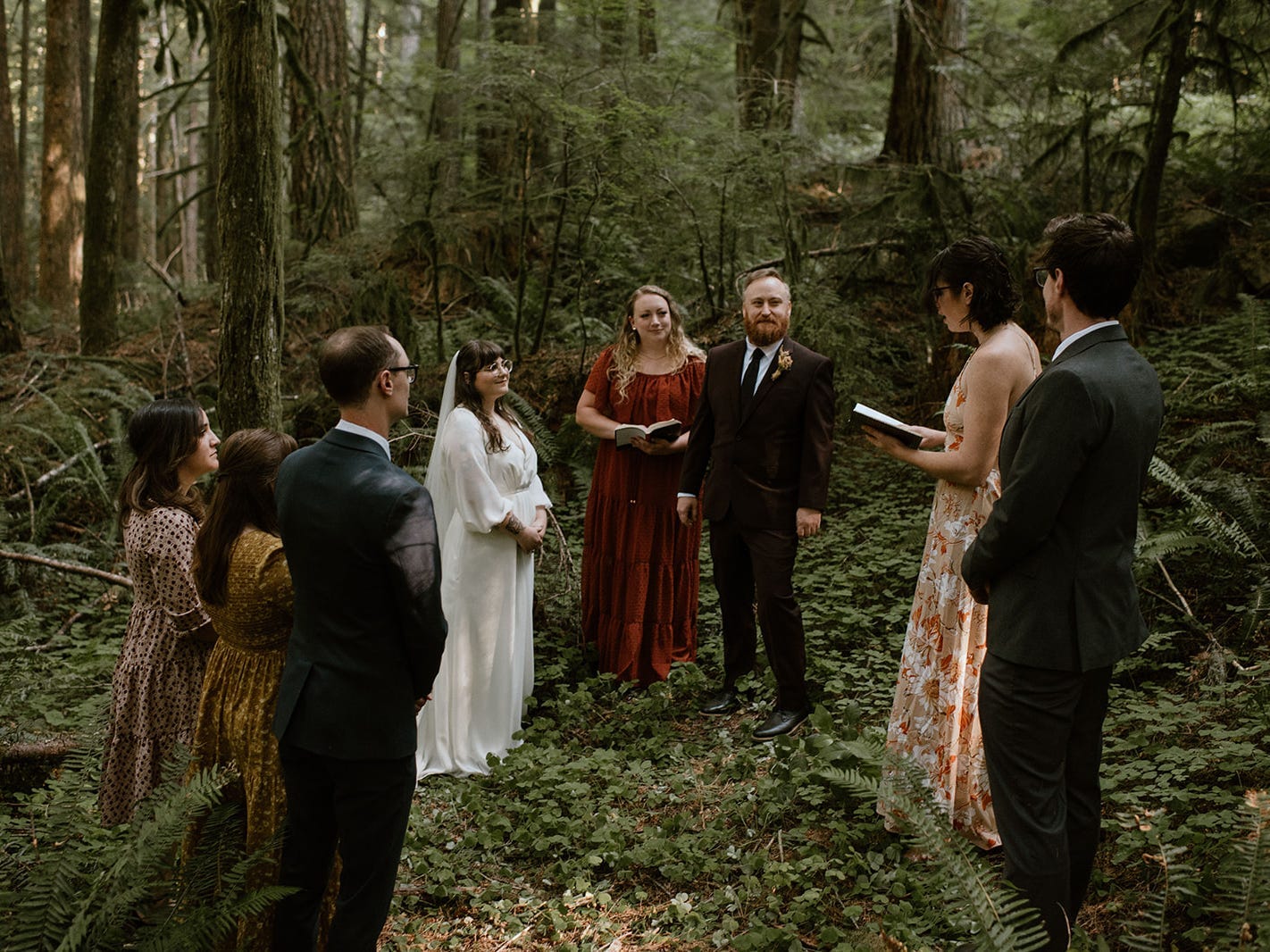 A wedding party and guests at a forest ceremony