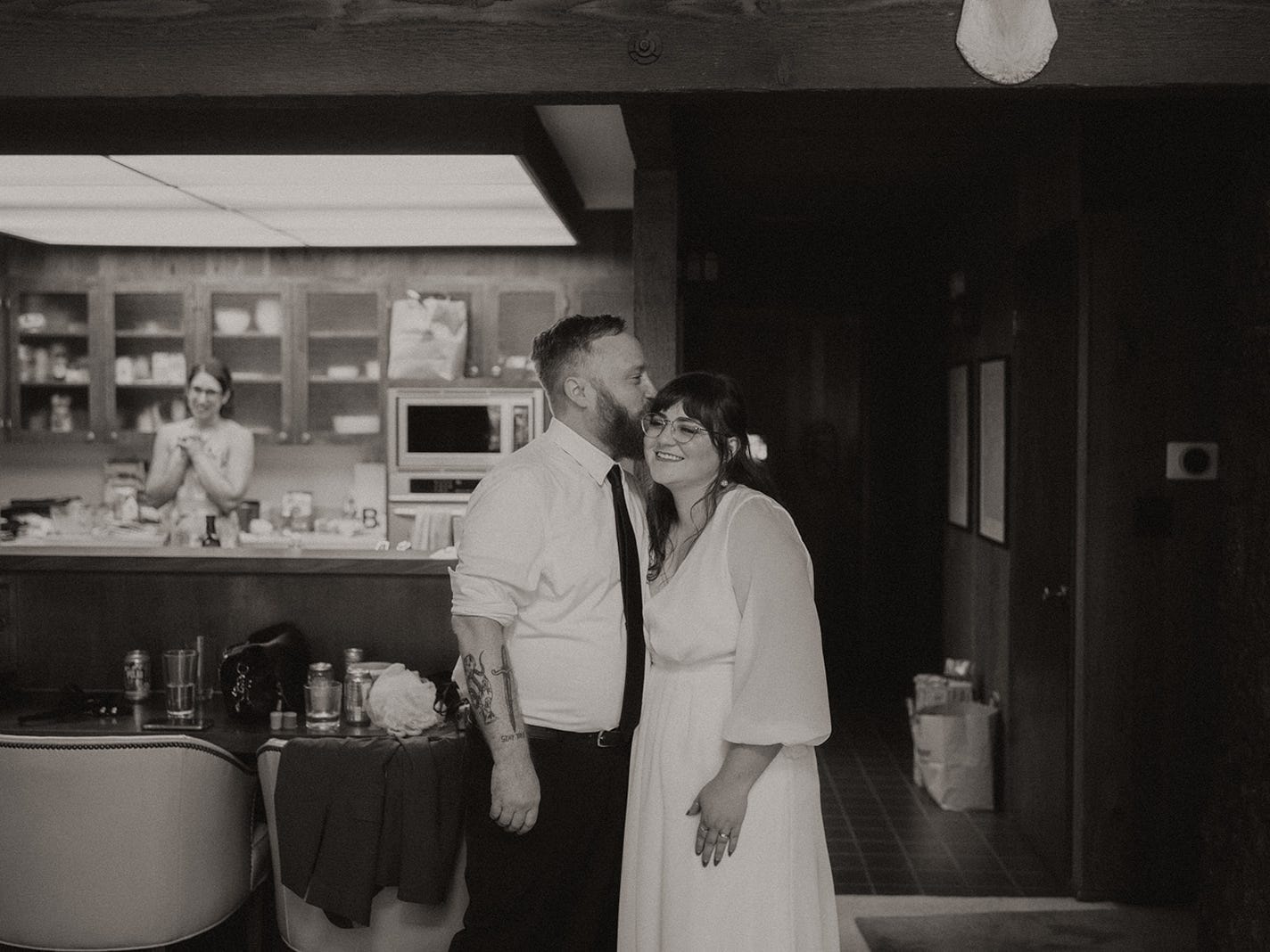 A person wearing a button down and tie kissing a person in a wedding dress