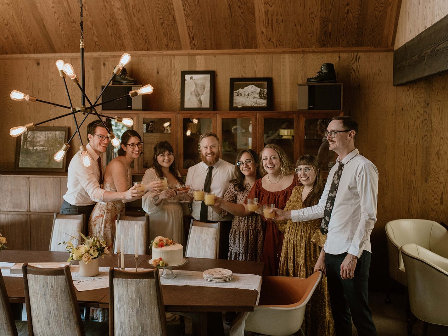 Friends at a wedding celebrator surrounding a table in a wooden room