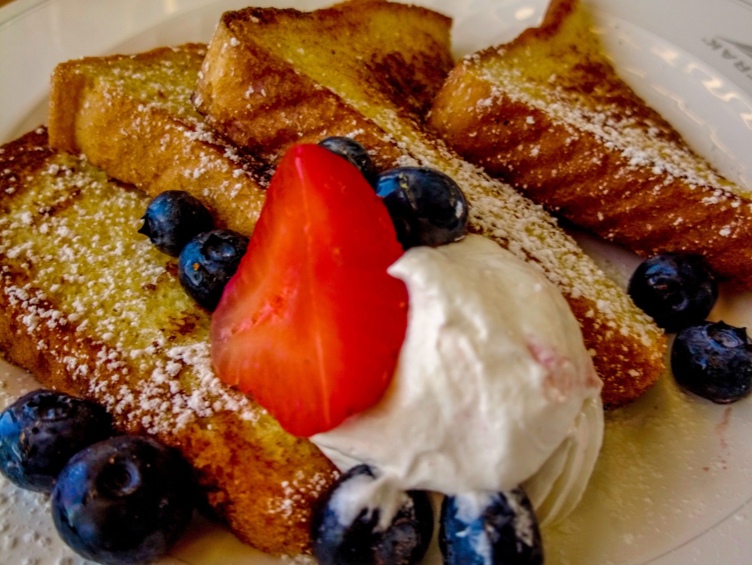 French toast with berries and cream on a white plate