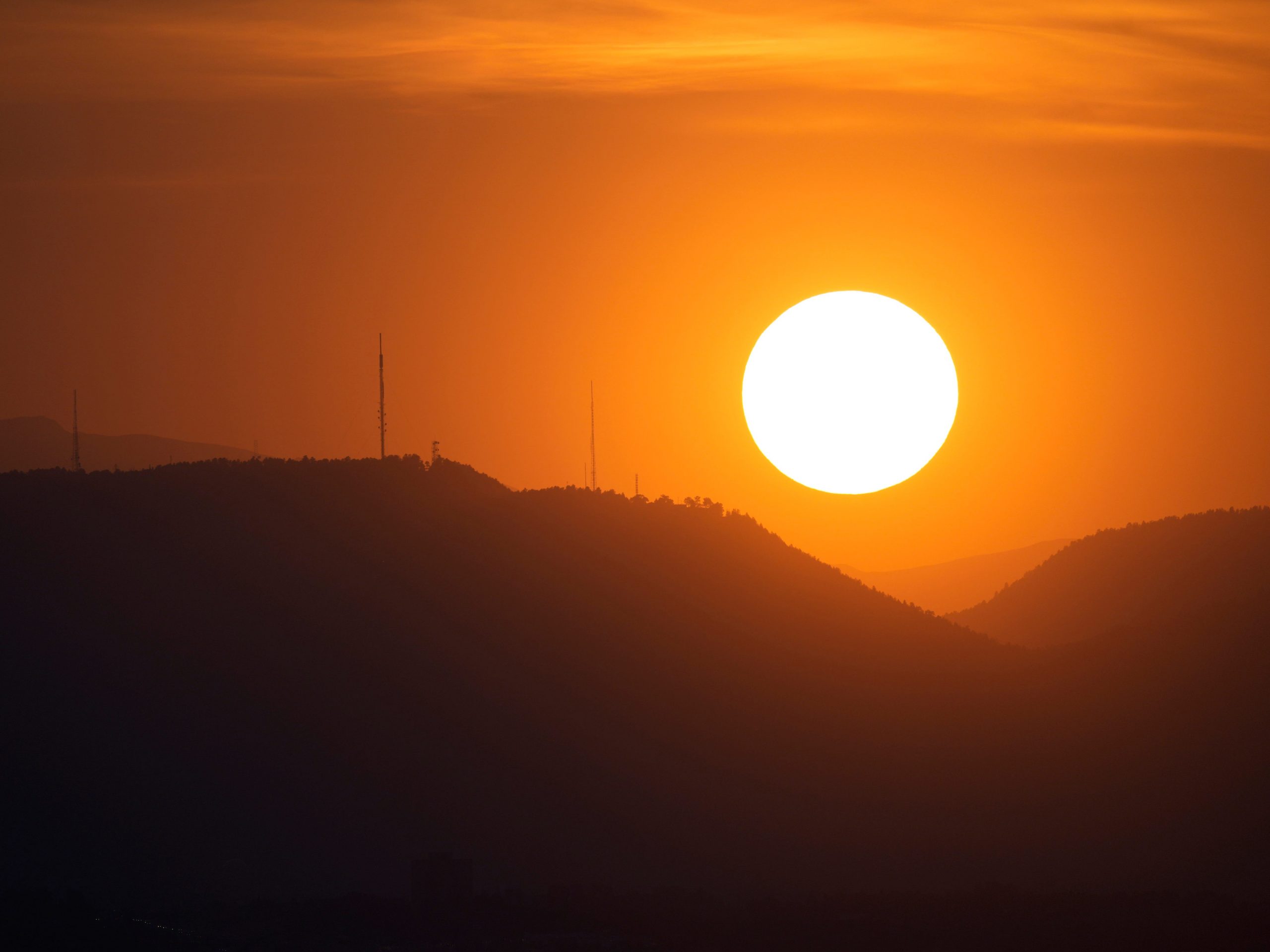 The sky is illuminated as the sun sets behind the Rocky Mountain Thursday, Sept. 10, 2021, in Denver.