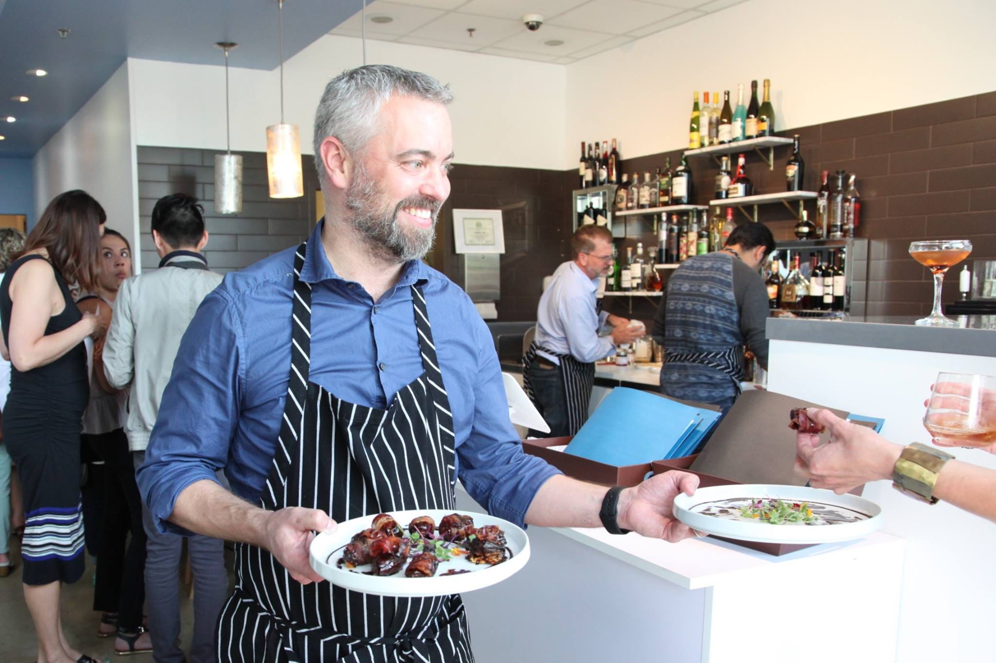 Phil Simonson, owner of Chocolate Lab, hands out food in restaurant.