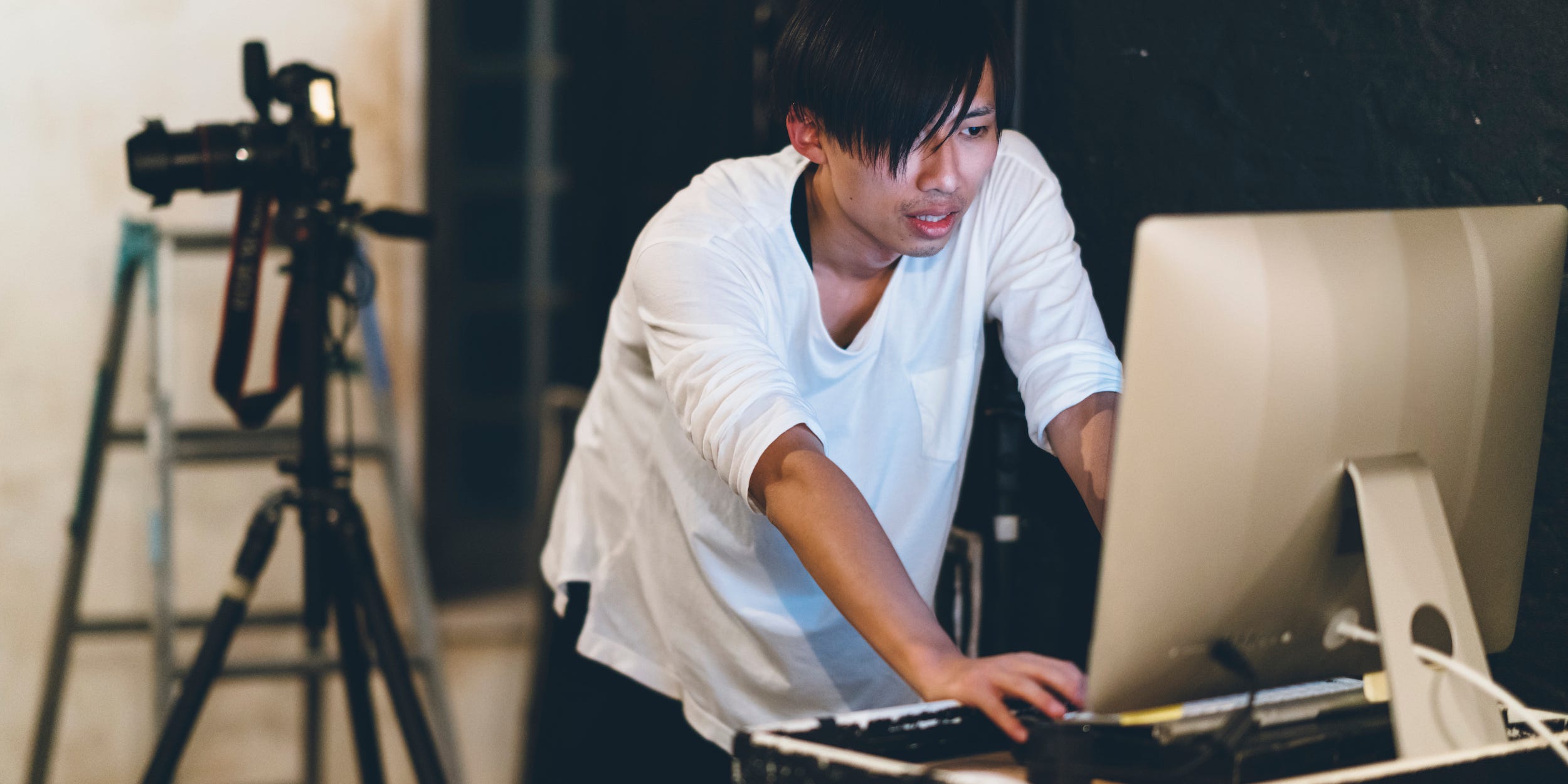 photographer editing photos on desktop computer with camera in background