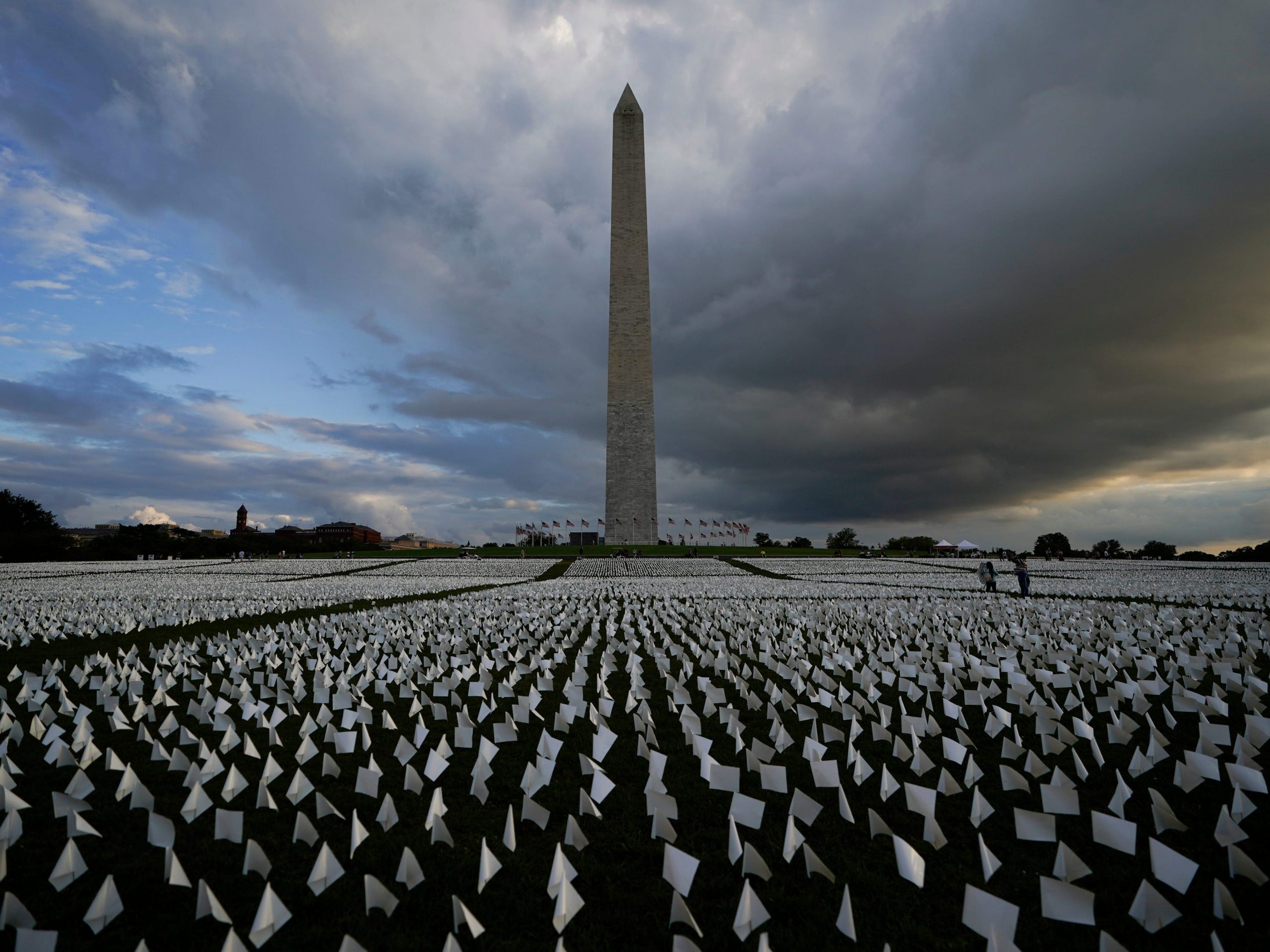 With the Washington Monument in the background, people look at white flags that are part of artist Suzanne Brennan Firstenberg's temporary art installation, "In America: Remember," in remembrance of Americans who have died of COVID-19, on the National Mall in Washington, Friday, Sept. 17, 2021.