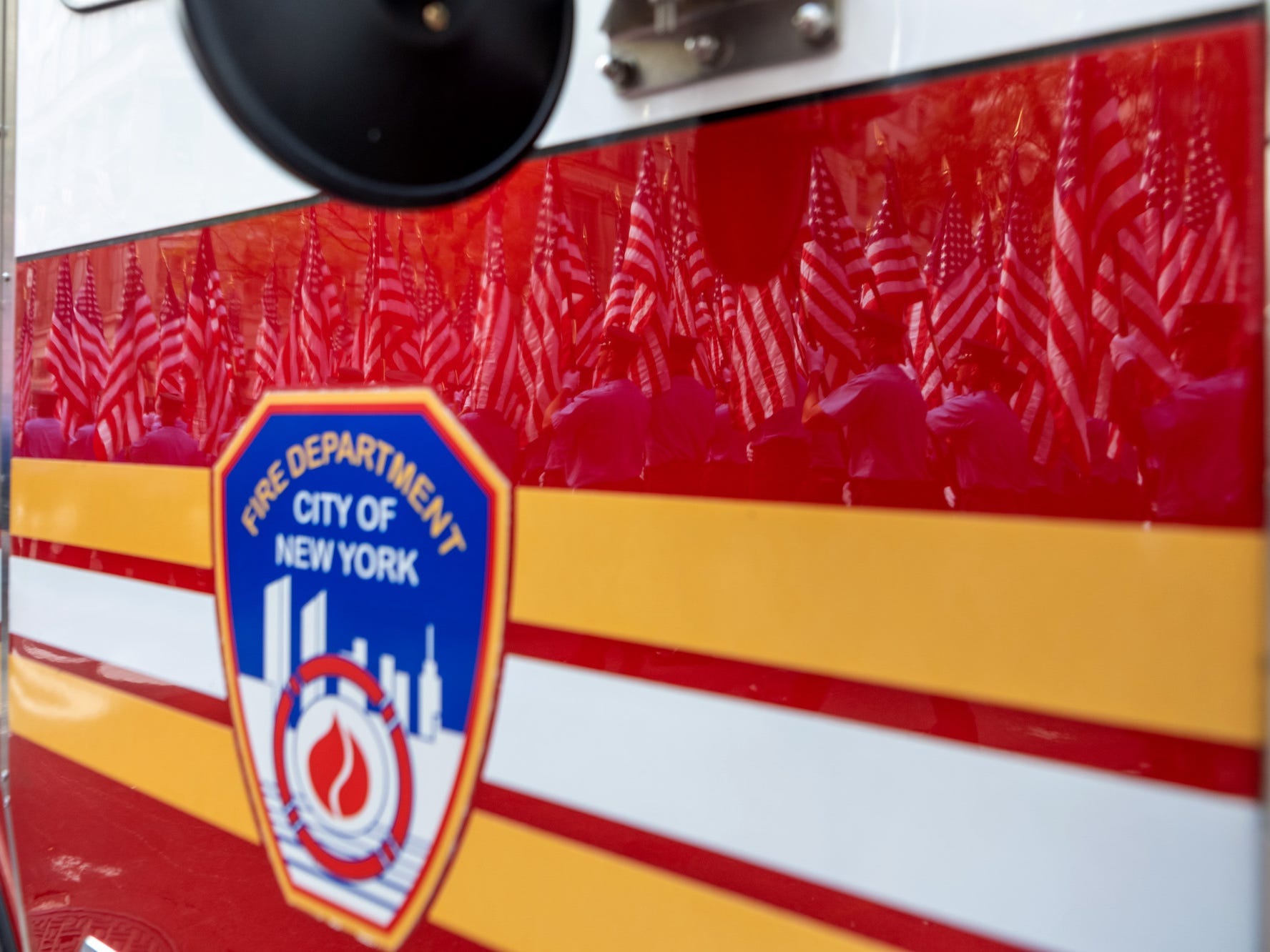 Members of the New York City Fire Department carrying American flags are reflected off a fire truck during a processional during the FDNY Memorial Service at St. Patrick's Cathedral on September 11, 2021 in New York City.