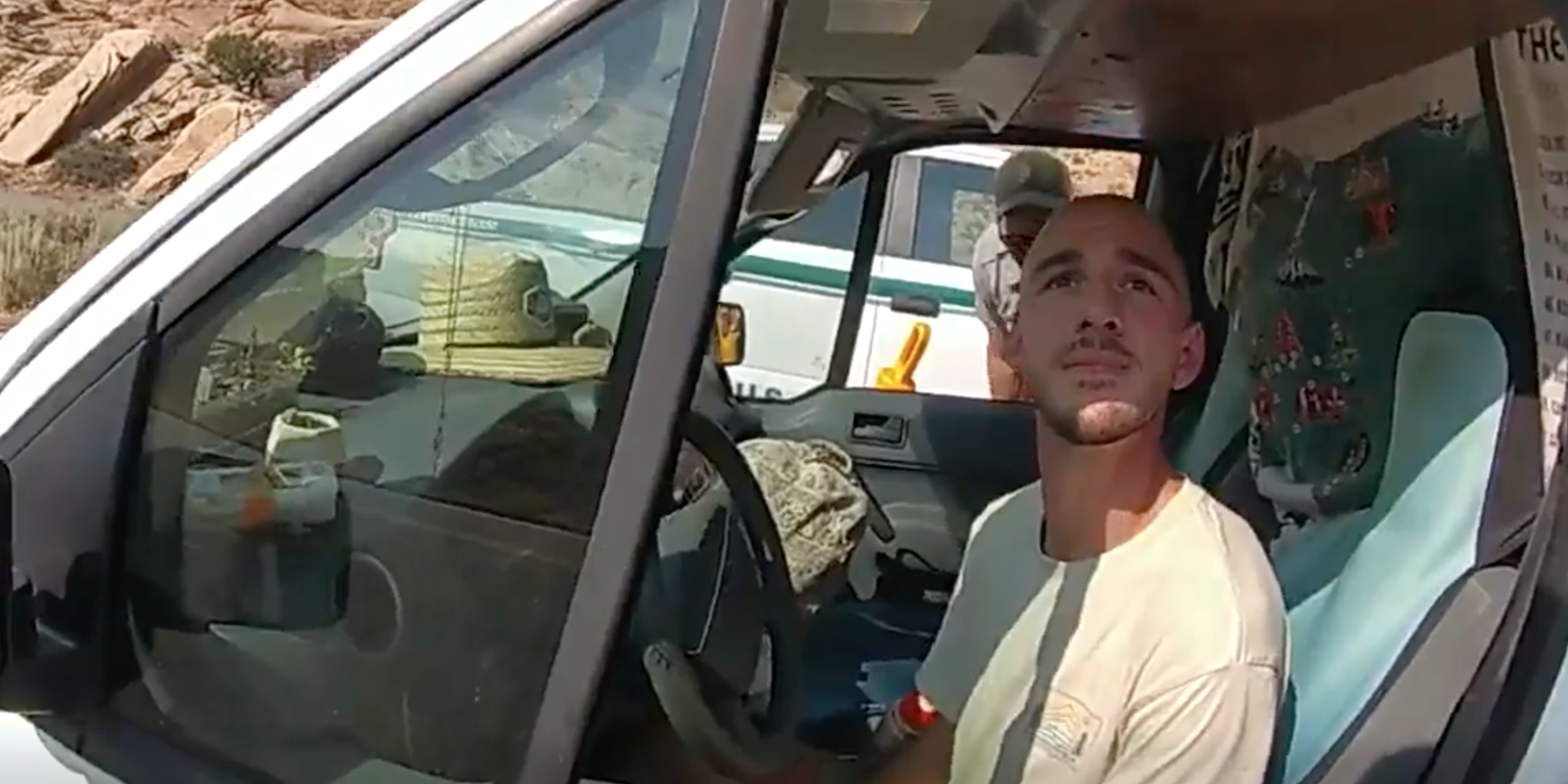 A Utah police officer's bodycam view of Brian Laundrie in the drivers' seat of a van. Laundrie is looking up at the officer.