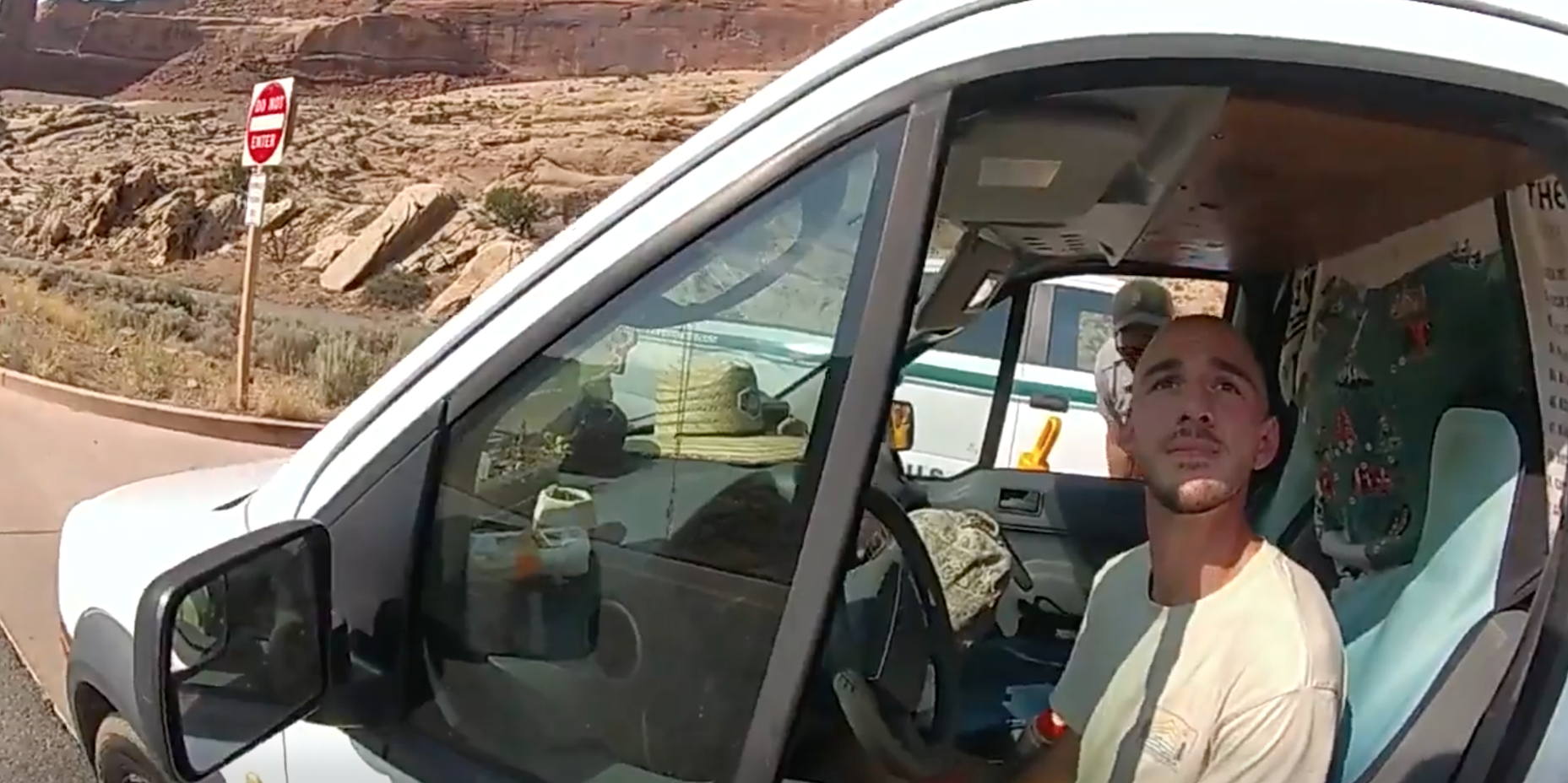 A Utah police officer's bodycam view of Brian Laundrie in the drivers' seat of a van. Laundrie is looking up at the officer.