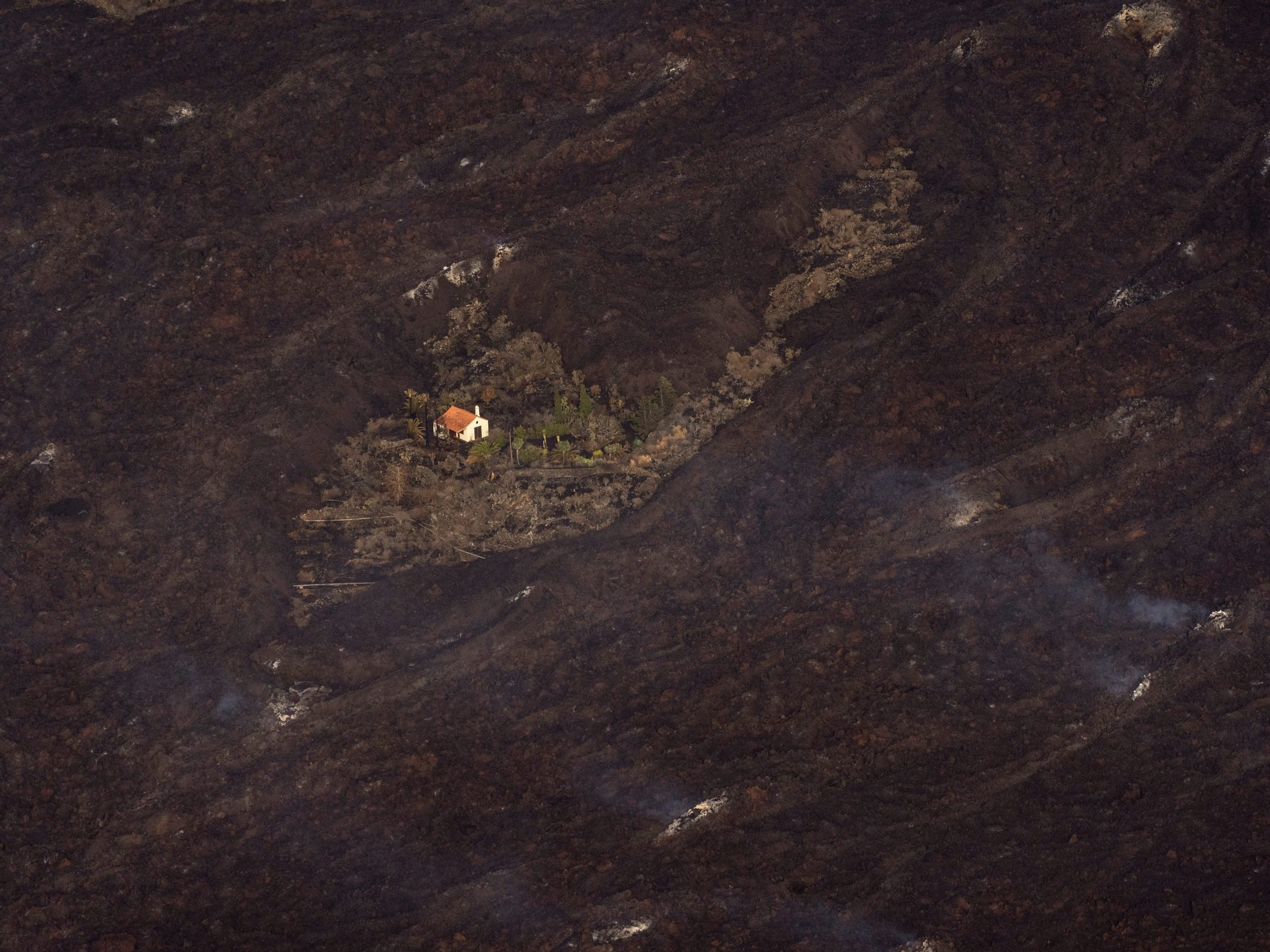 Lava from a volcano eruption surrounds a house on the island of La Palma in the Canaries, Spain, Thursday, Sept. 23, 2021.