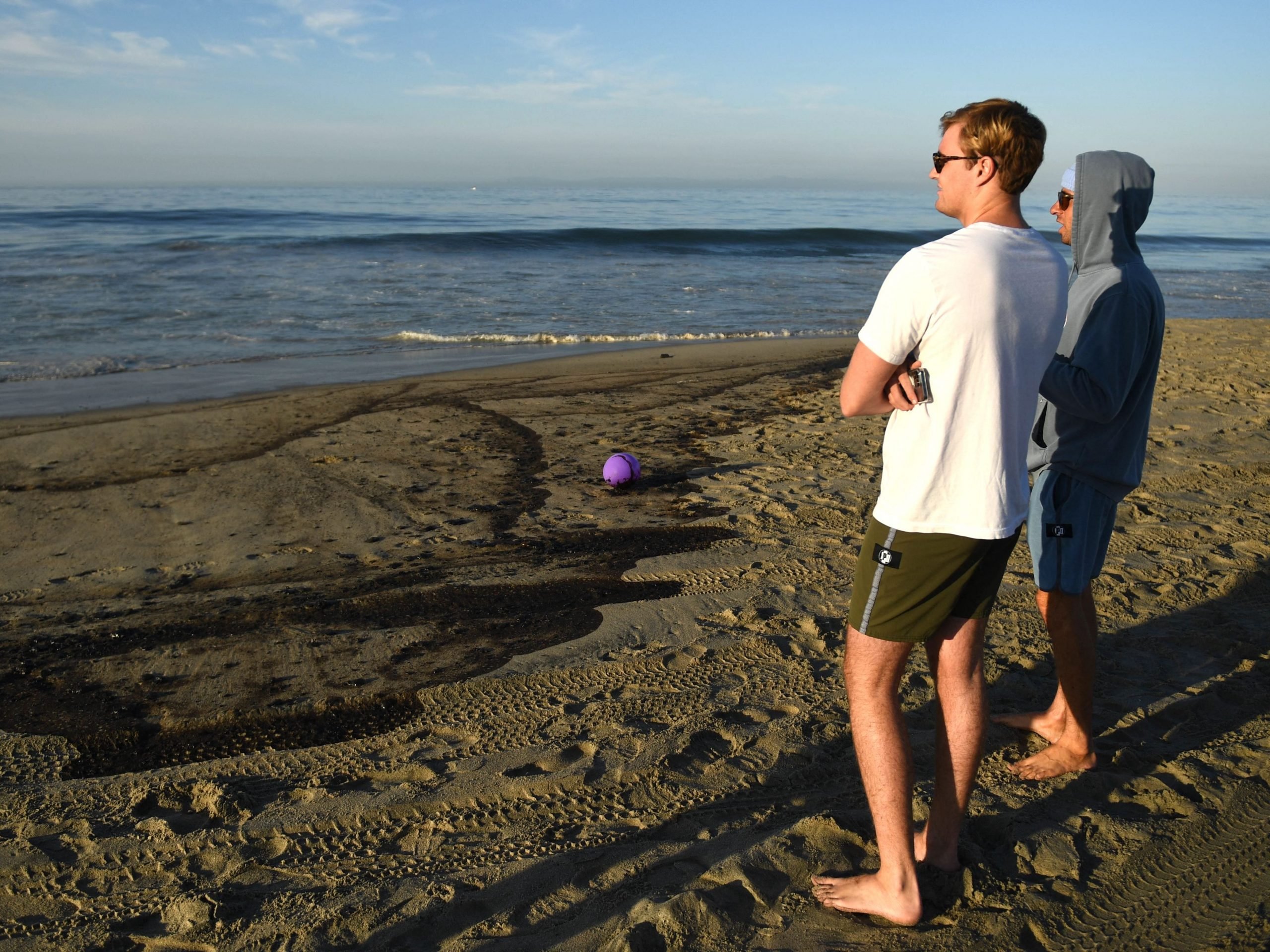 People on a beach looking at oil.