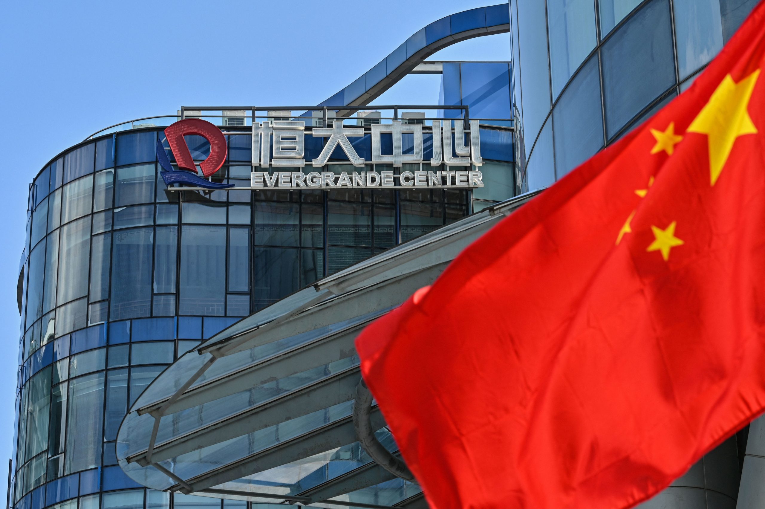 A view of Evergrande Center building with a Chinese flag in the foreground.