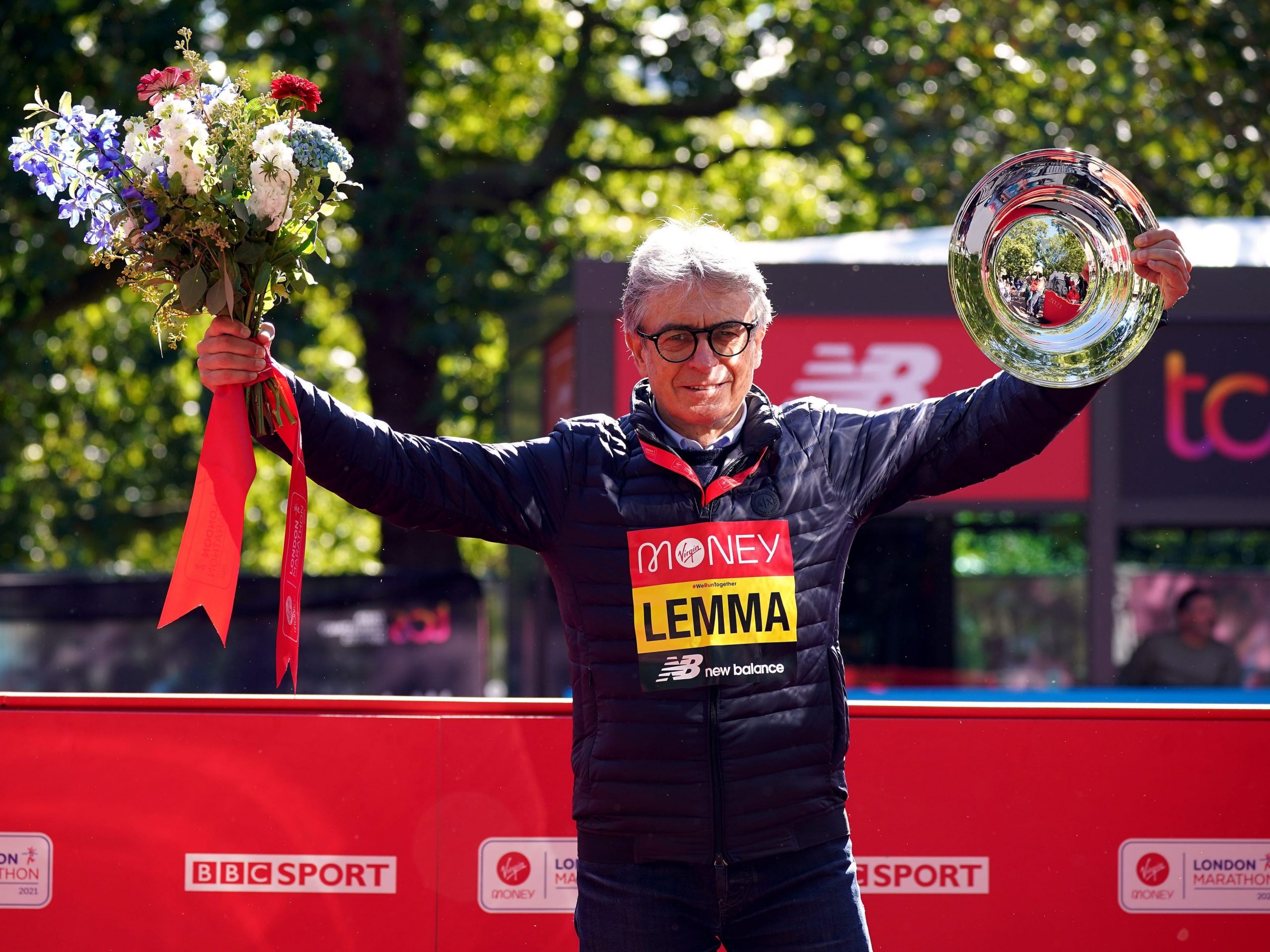 Gianni Demadonna waves flowers and a trophy at the London Marathon