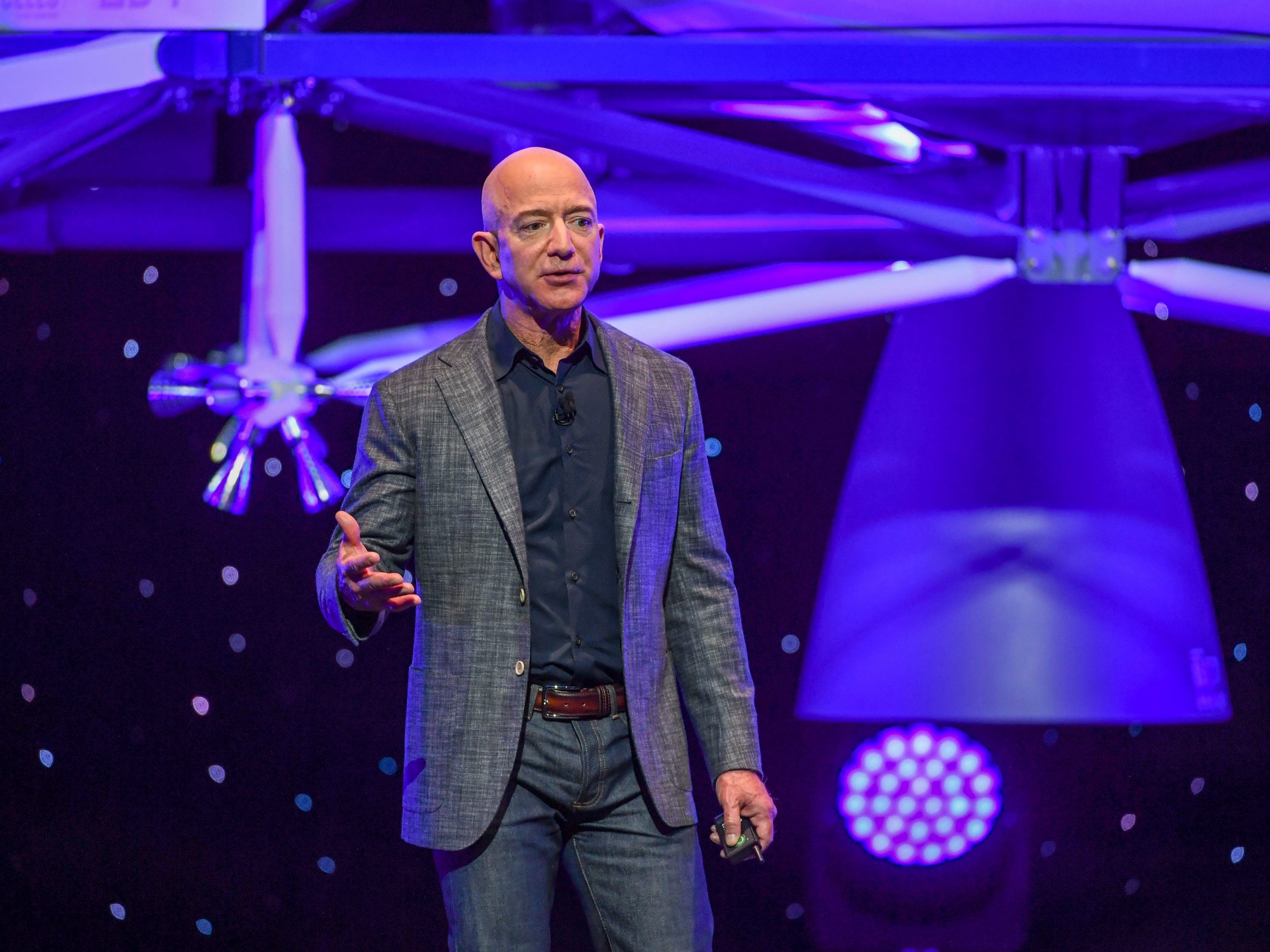 Jeff Bezos speaks with his lunar lander hovering in the background.