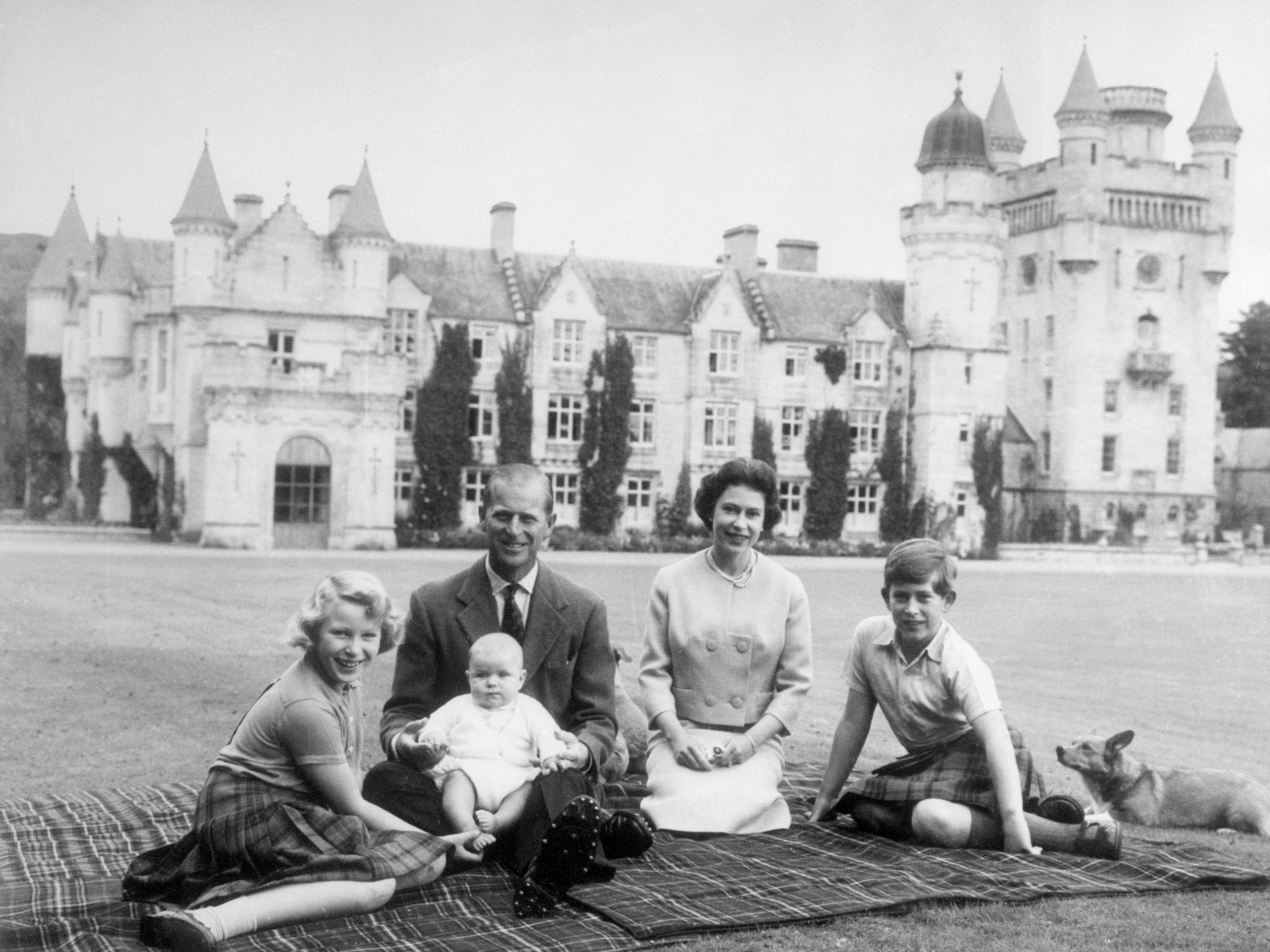 Baby Prince Andrew perches on Prince Philip's lap during a picnic on the grounds of Balmoral Castle. Also pictured are Queen Elizabeth, Prince Charles, and Princess Anne.