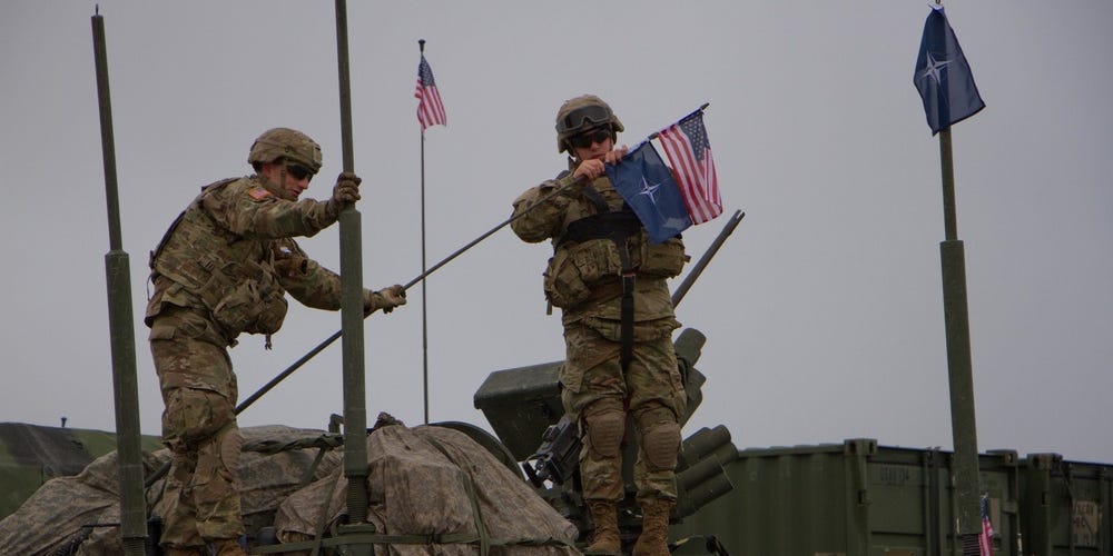 Soldiers assigned to 3d Squadron, 2d Cavalry Regiment, U.S. Army place U.S. and NATO flags on the antenna of their Stryker Combat Vehicle before leaving on a 1,100 km road march from Rose Barracks, Germany to Orzysz, Poland.