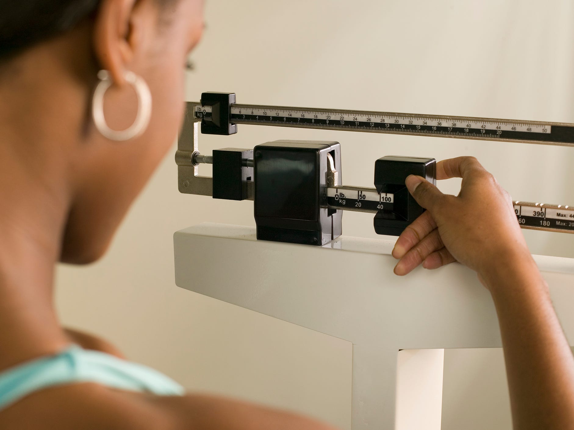 a side view of a person's face looking at and adjusting a weight scale as they are weighing themselves