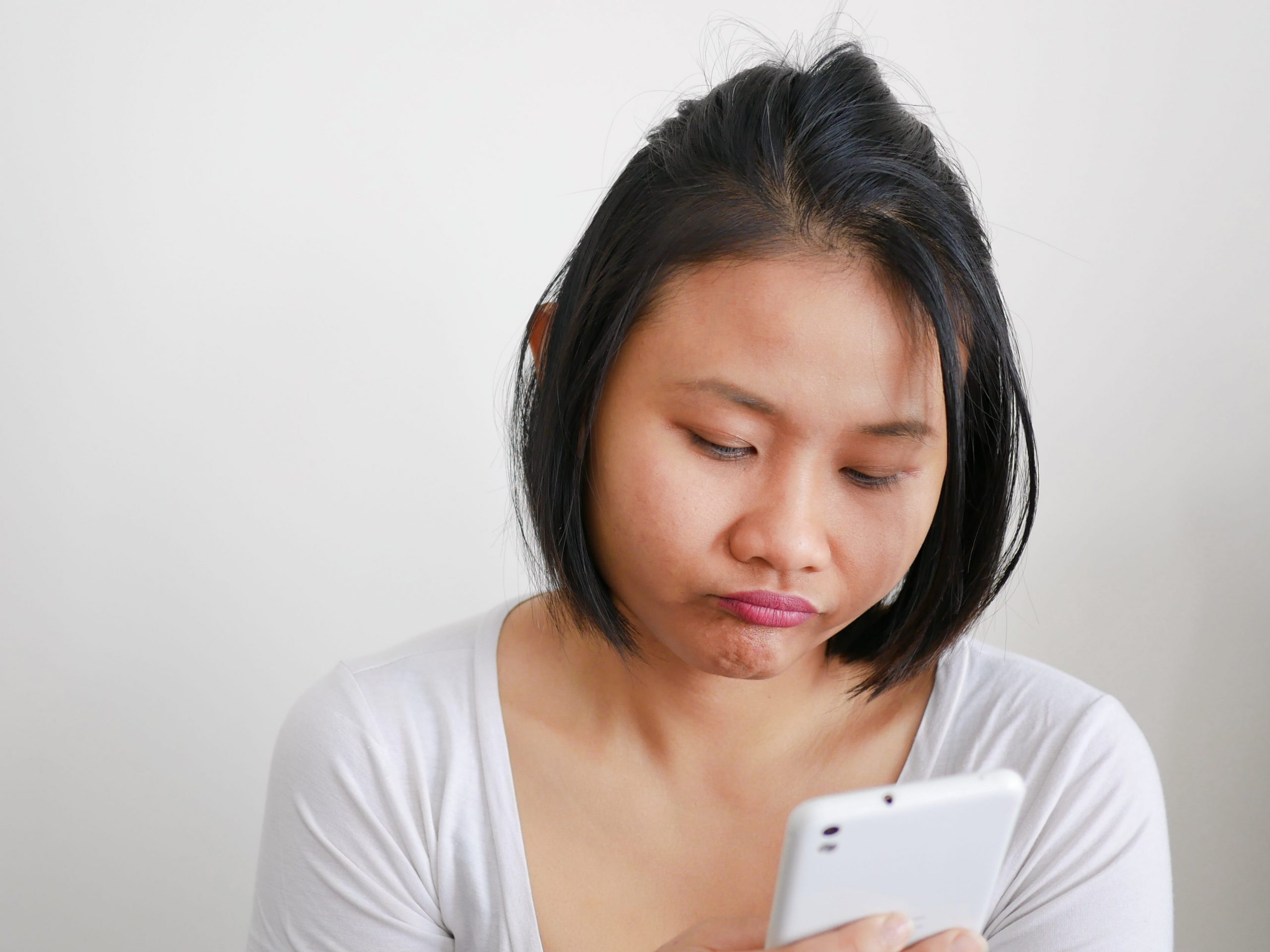 Woman looking down at her phone, waiting.