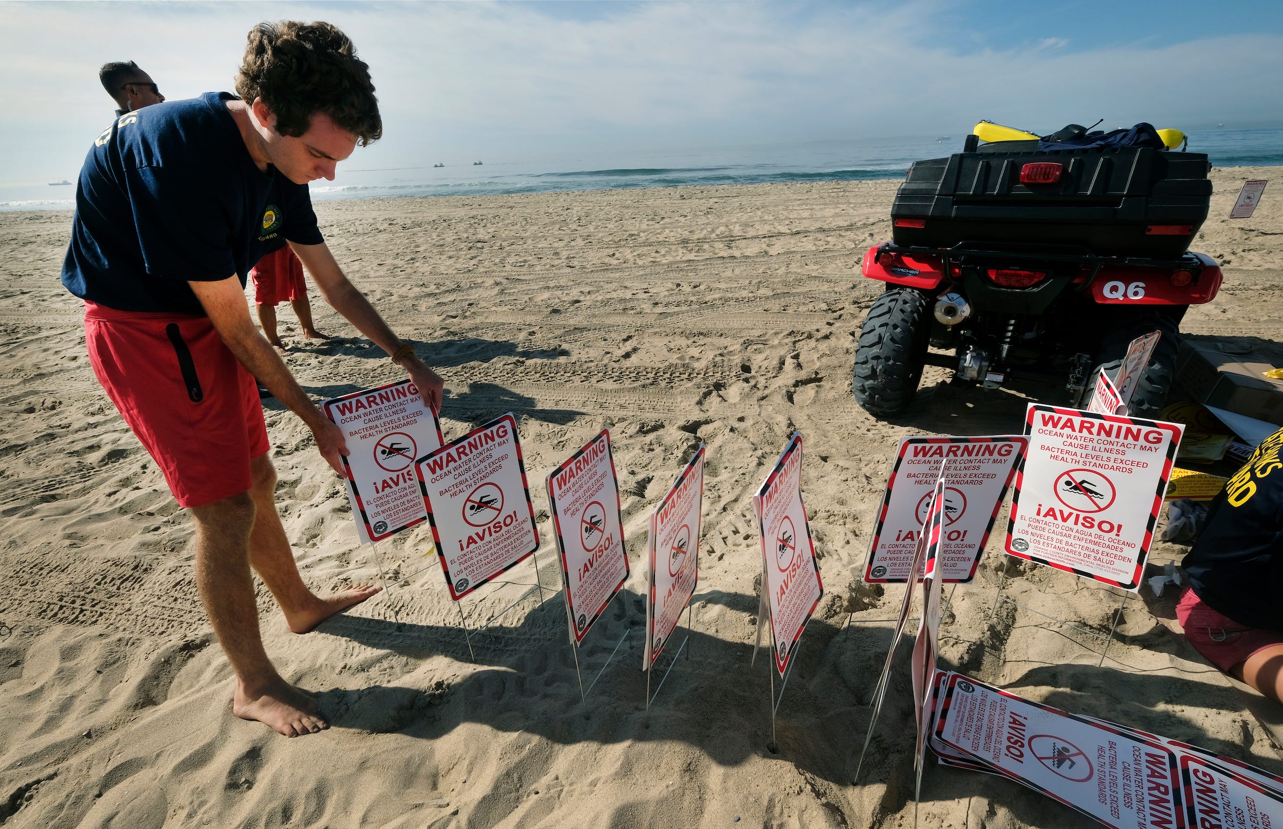 lifeguards post warning signs about oil spill on beaches