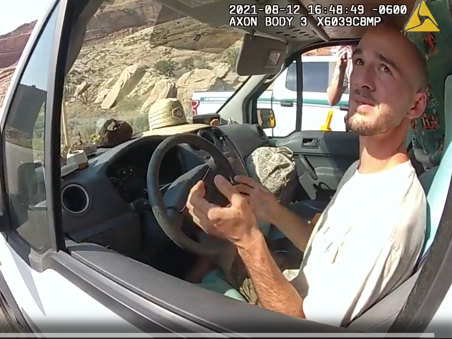 A Utah police officer's bodycam view of Brian Laundrie in the drivers' seat of a van. Laundrie is gesturing while talking.