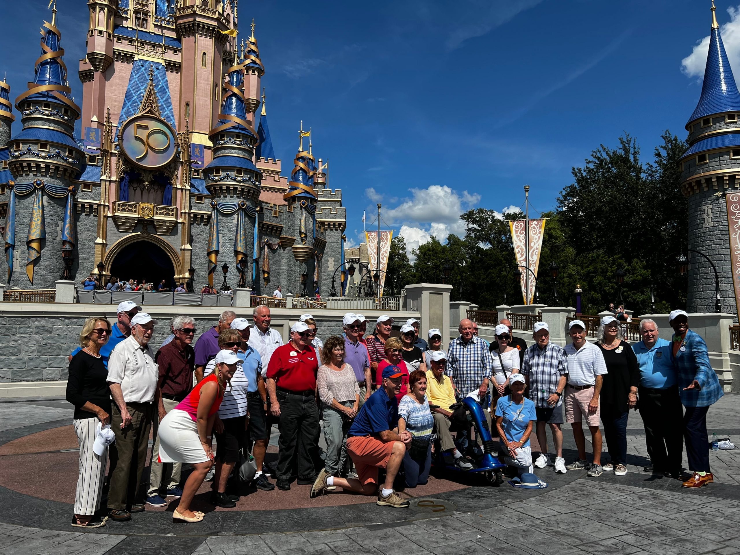 opening day cast members taking a photo in front of the castle during disney world 50th anniversary