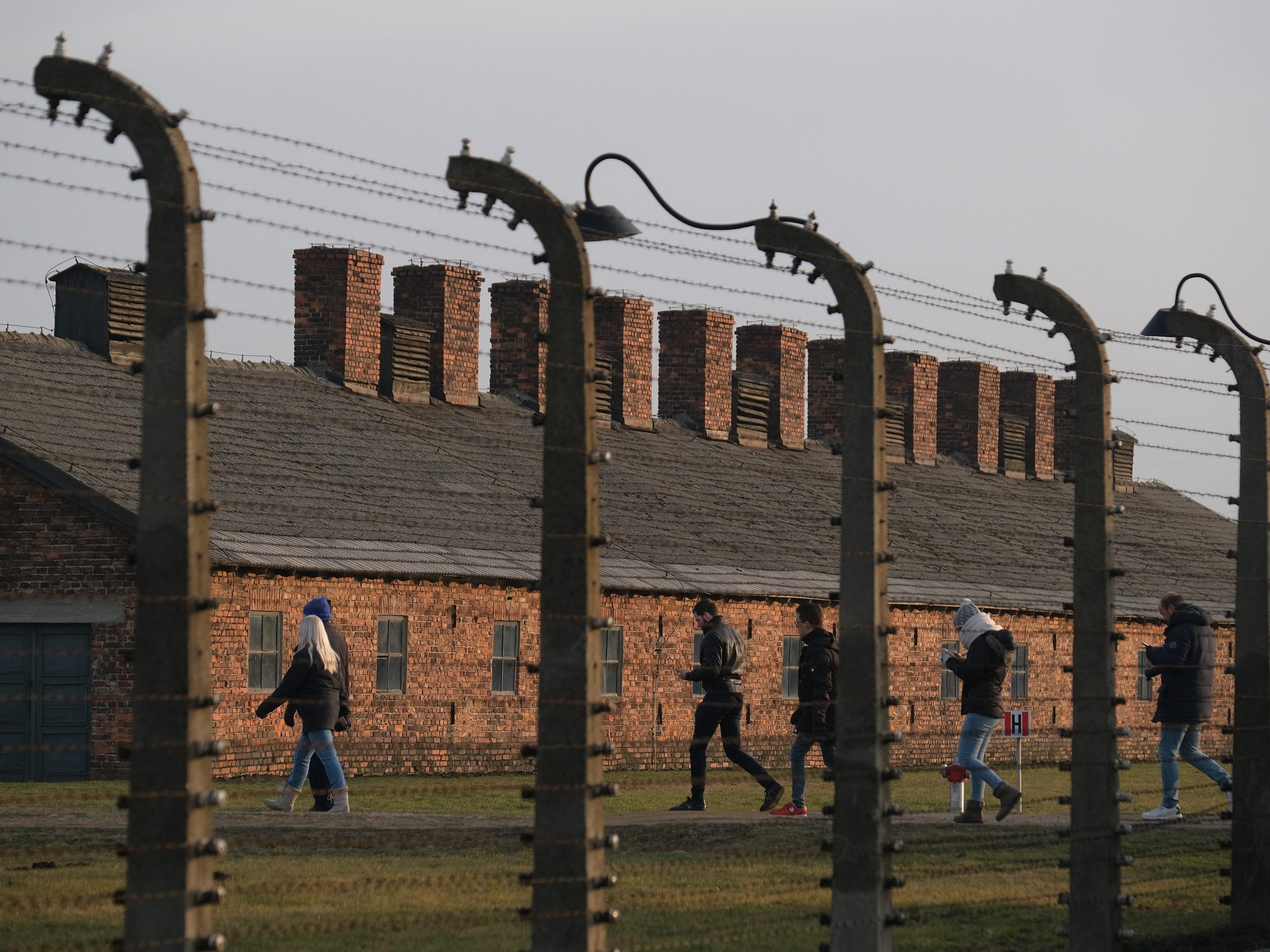 Visitors walks past barbed wire and prisoner barracks at the former Auschwitz-Birkenau German concentration camp near Oswiecim, Poland.