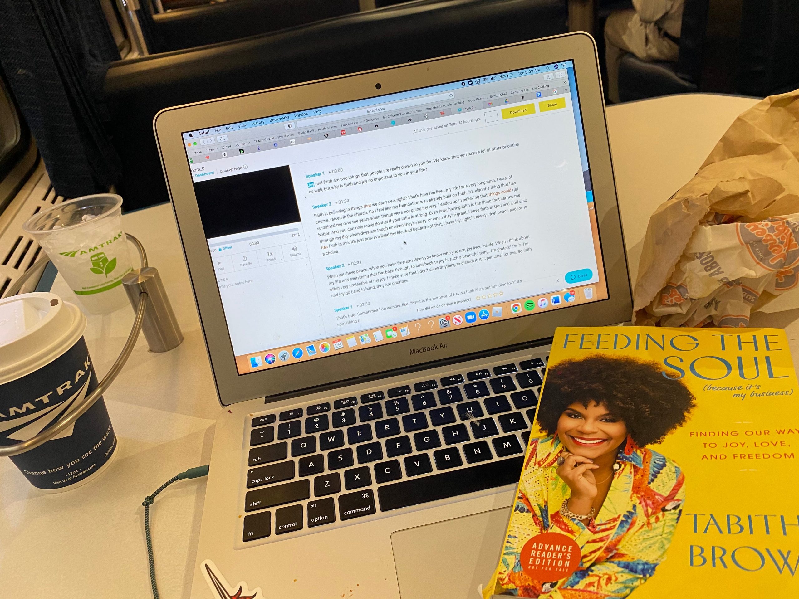 The writer with her laptop, coffee, and a book on the train