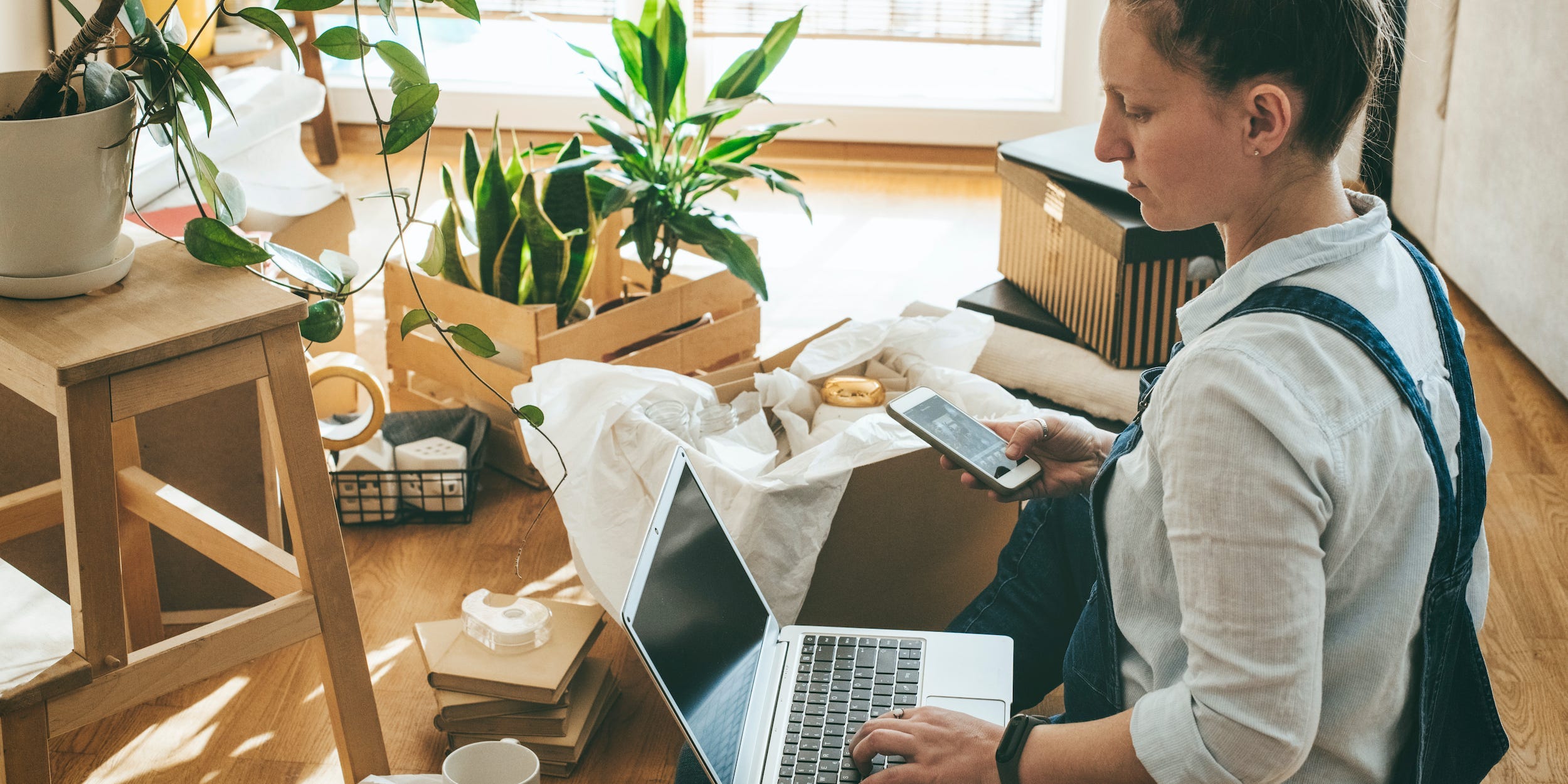 woman unpacking boxes with laptop and phone