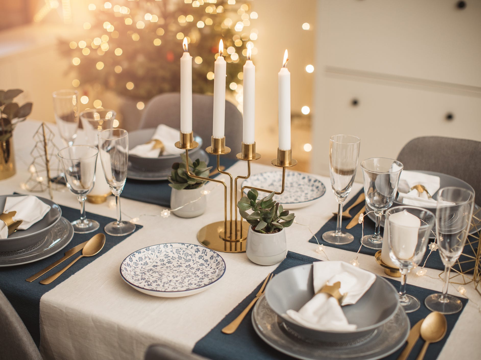 An elegant dinner table with a white table cloth, blue placemats, and a brass candelabra at the center