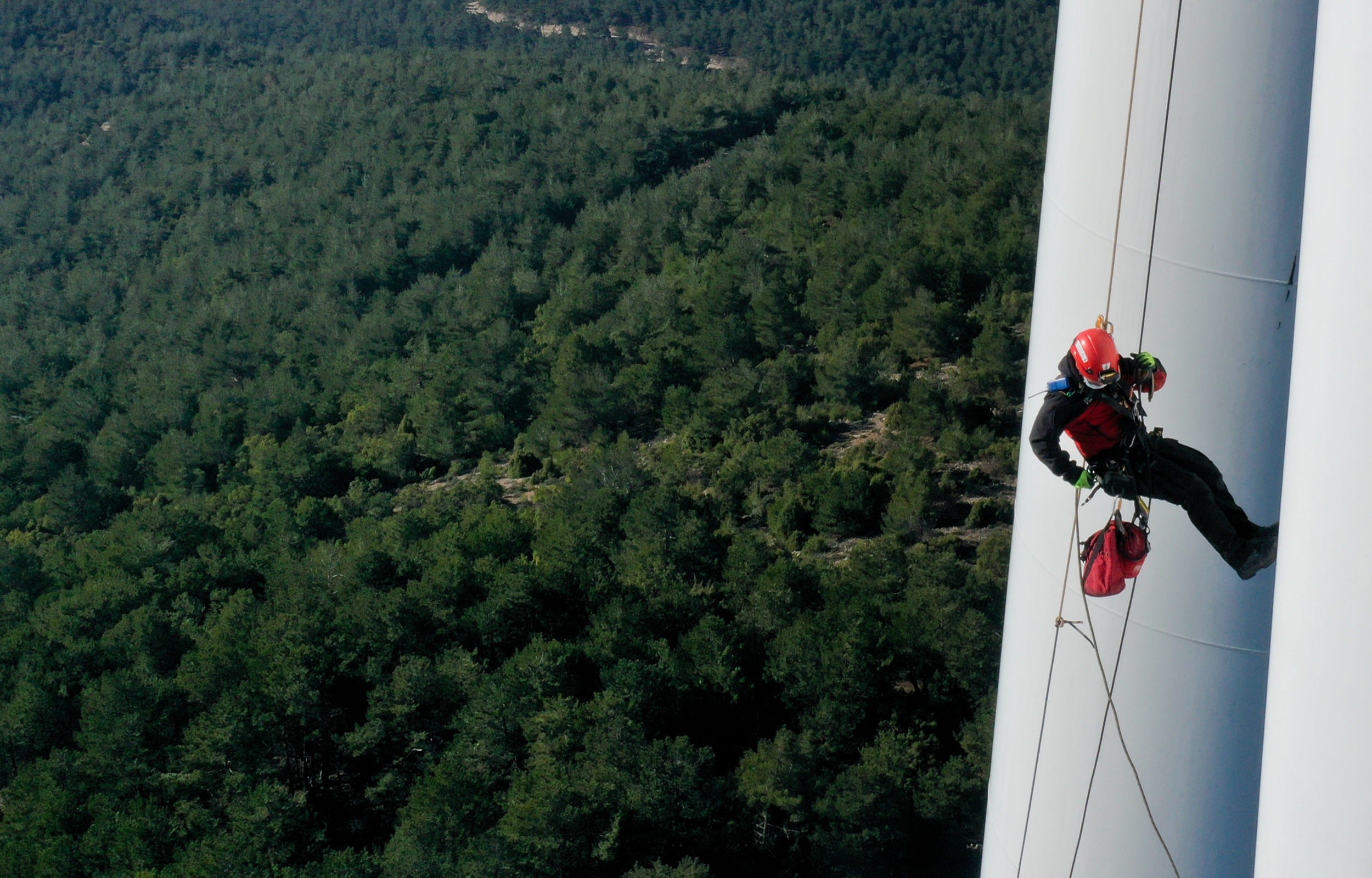 A rope access technician carries out maintenance service on a wind turbine blade