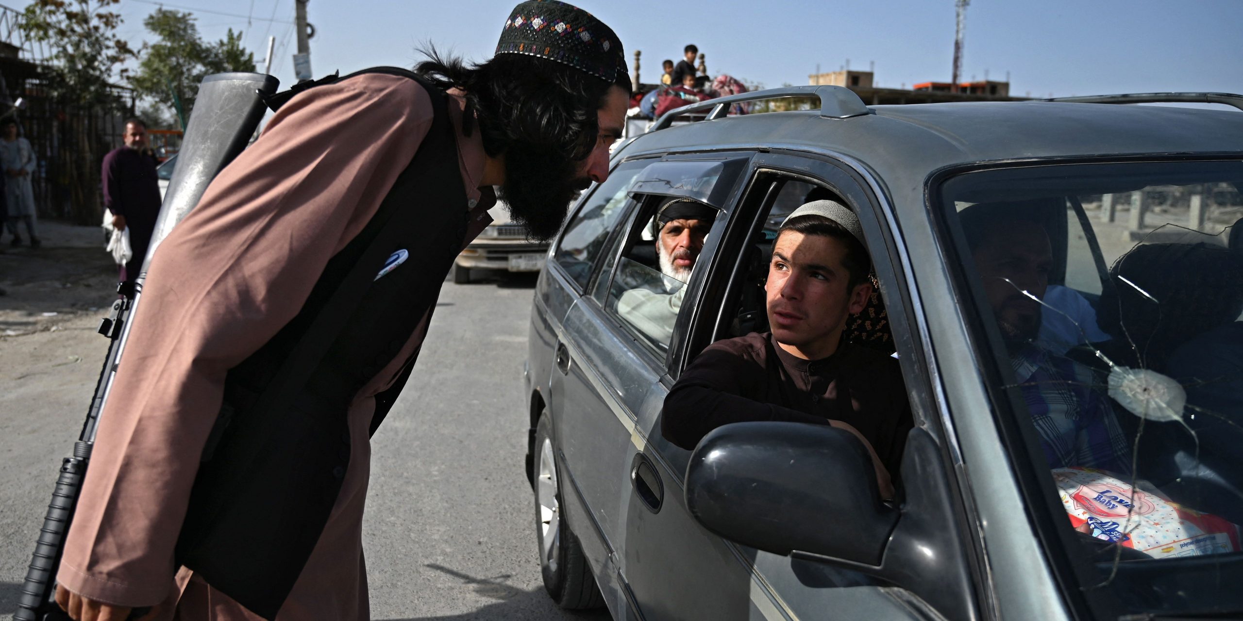 Taliban policeman peer into a car full of people at a checkpoint.