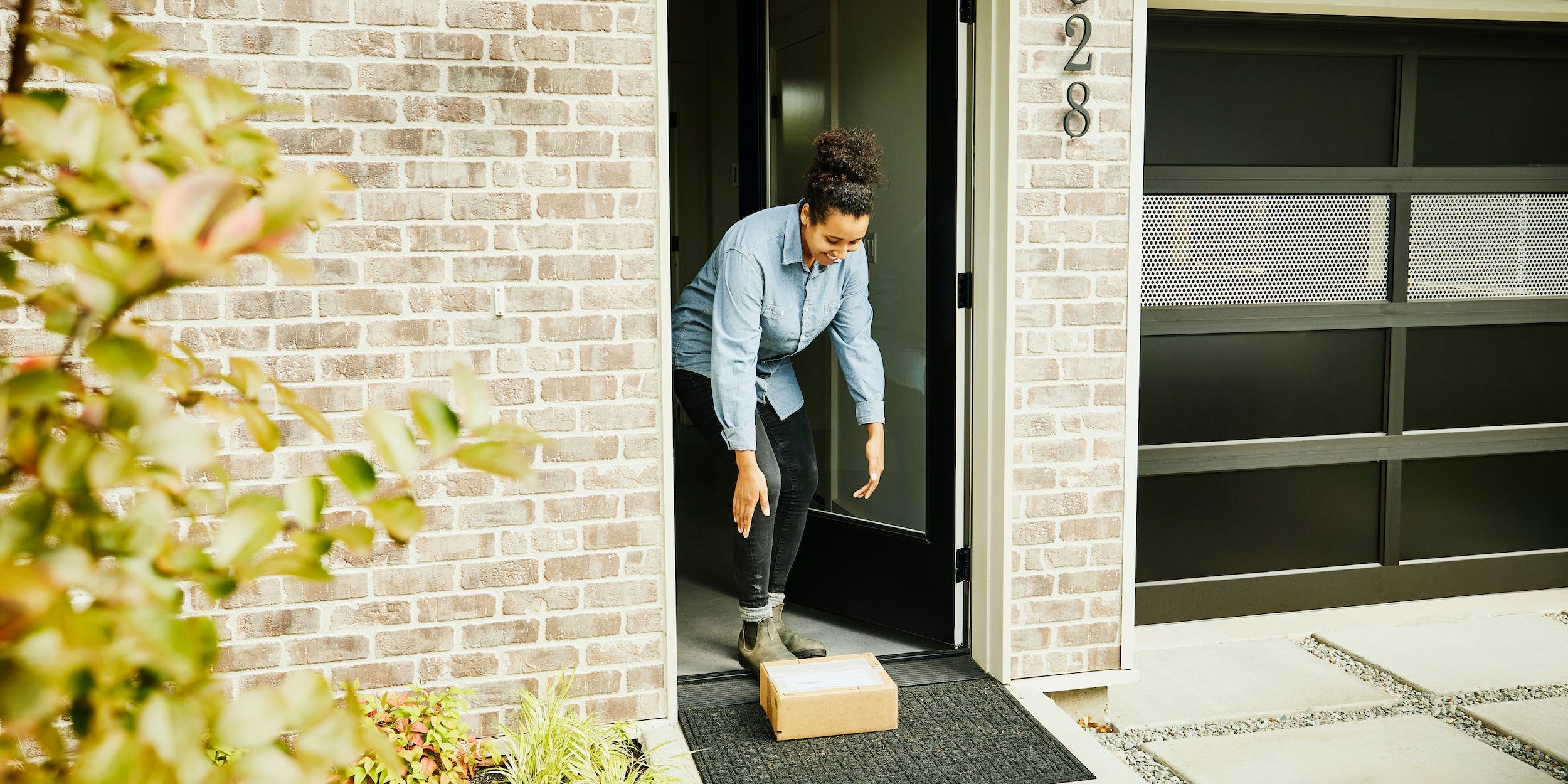 Woman picking up package delivery on front doorstep