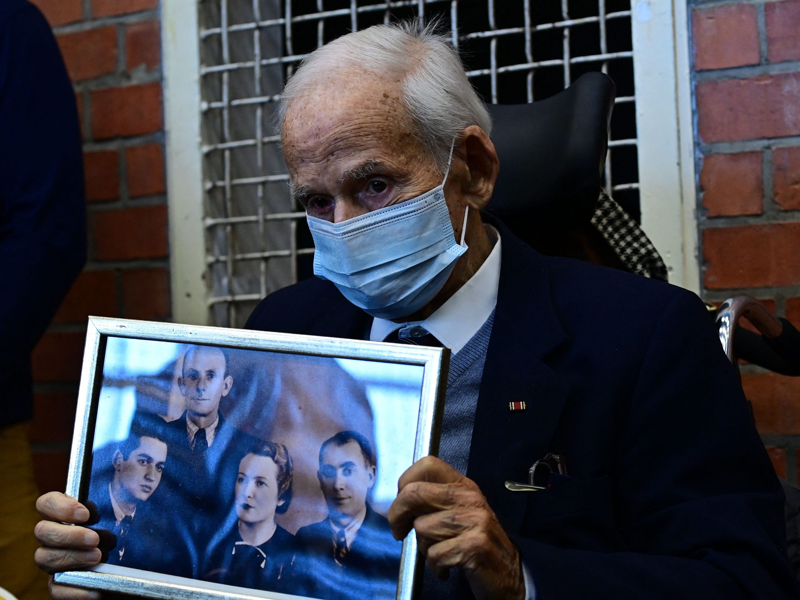 A Holocaust survivor holds a photo of his family.