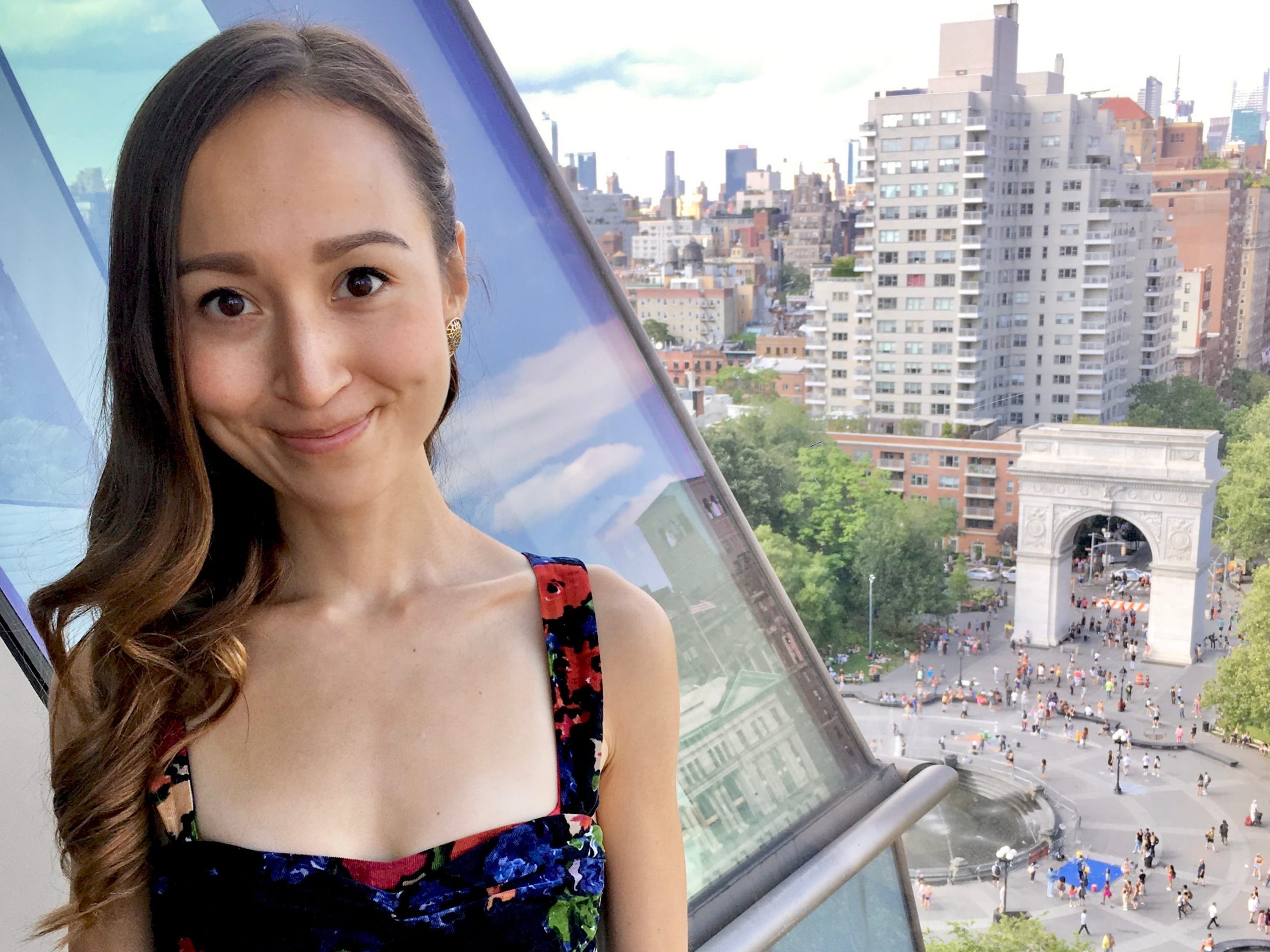 The writer standing in front of a window overlooking the busy Washington Square Arch