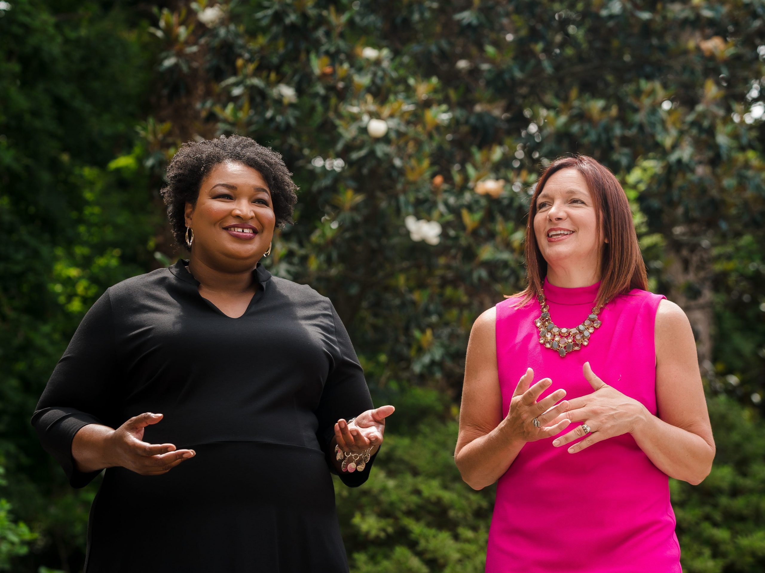 Stacey Abrams and Lara Hodgson, Now co-founders, pose outside in front of hedge