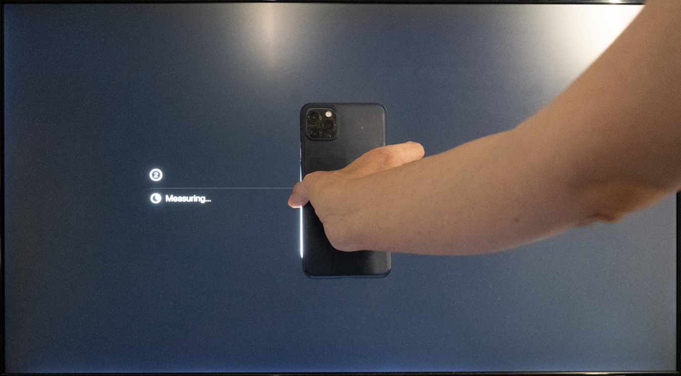 [apple-tv-color-calibration4.png:  / Holding an iPhone close to the Apple TV Color Calibration screen.]