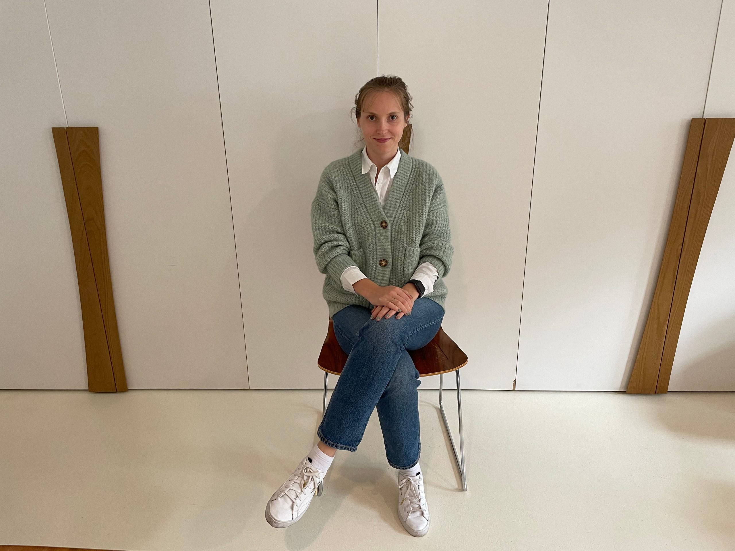 Woman sitting in chair in front of empty white wall