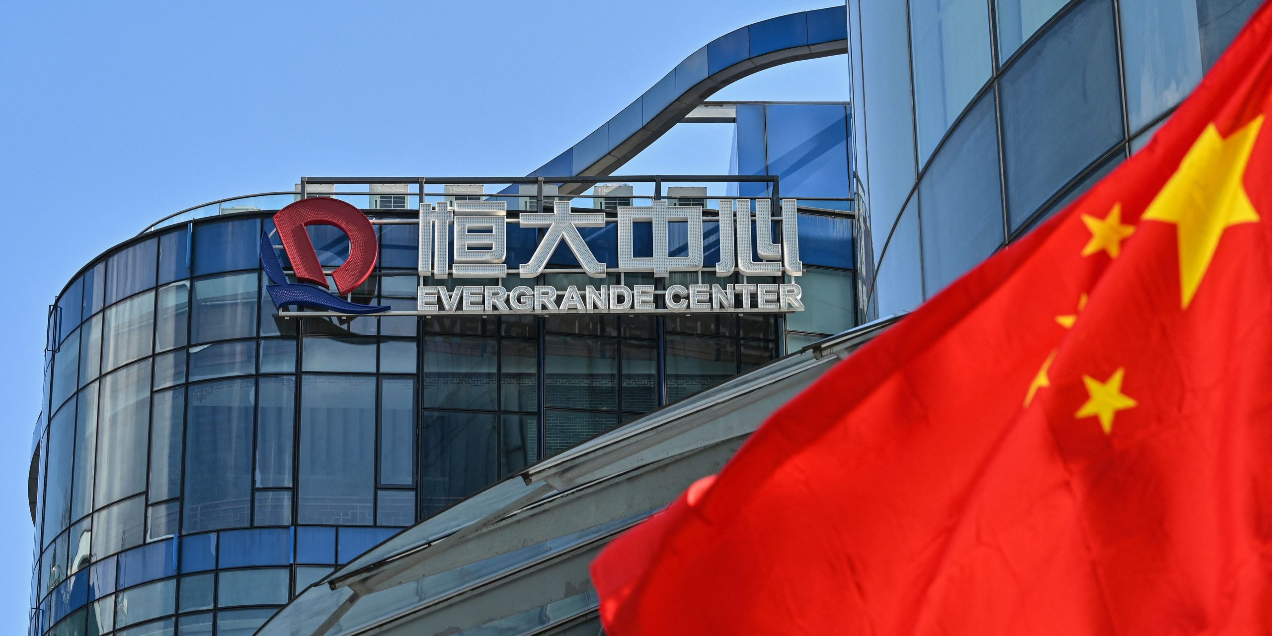 A view of Evergrande Center building with a Chinese flag in the foreground.